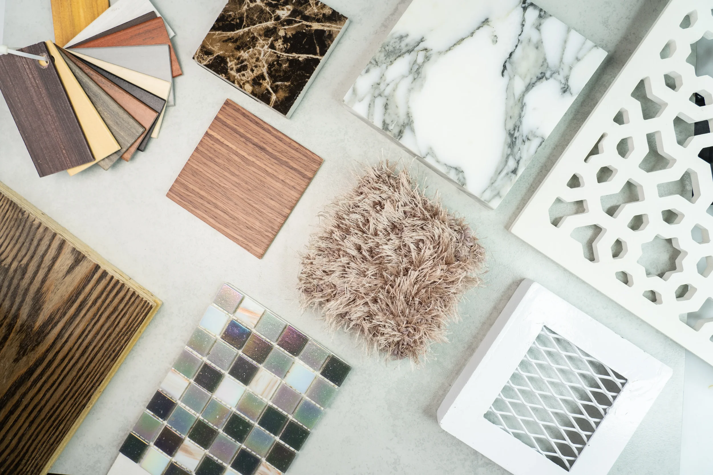 A selection of interior design samples including carpet swatches, wood, marble, mosaic tiles, and decorative panels.