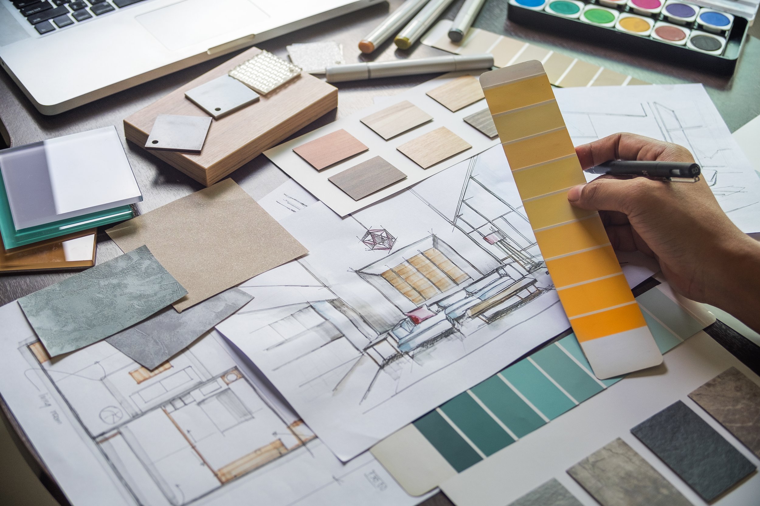 Interior design workspace with sketches, color swatches, and samples including paint, fabric, and materials.