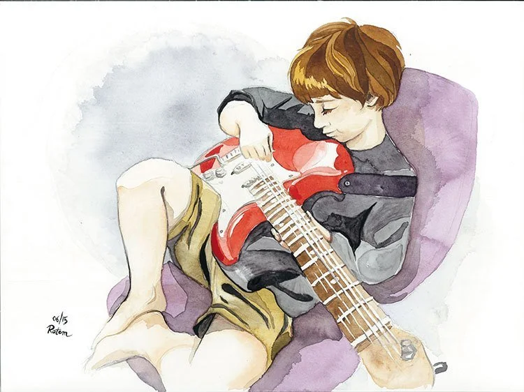 A boy with brown hair sitting on a purple cushion, playing a red and white electric guitar.