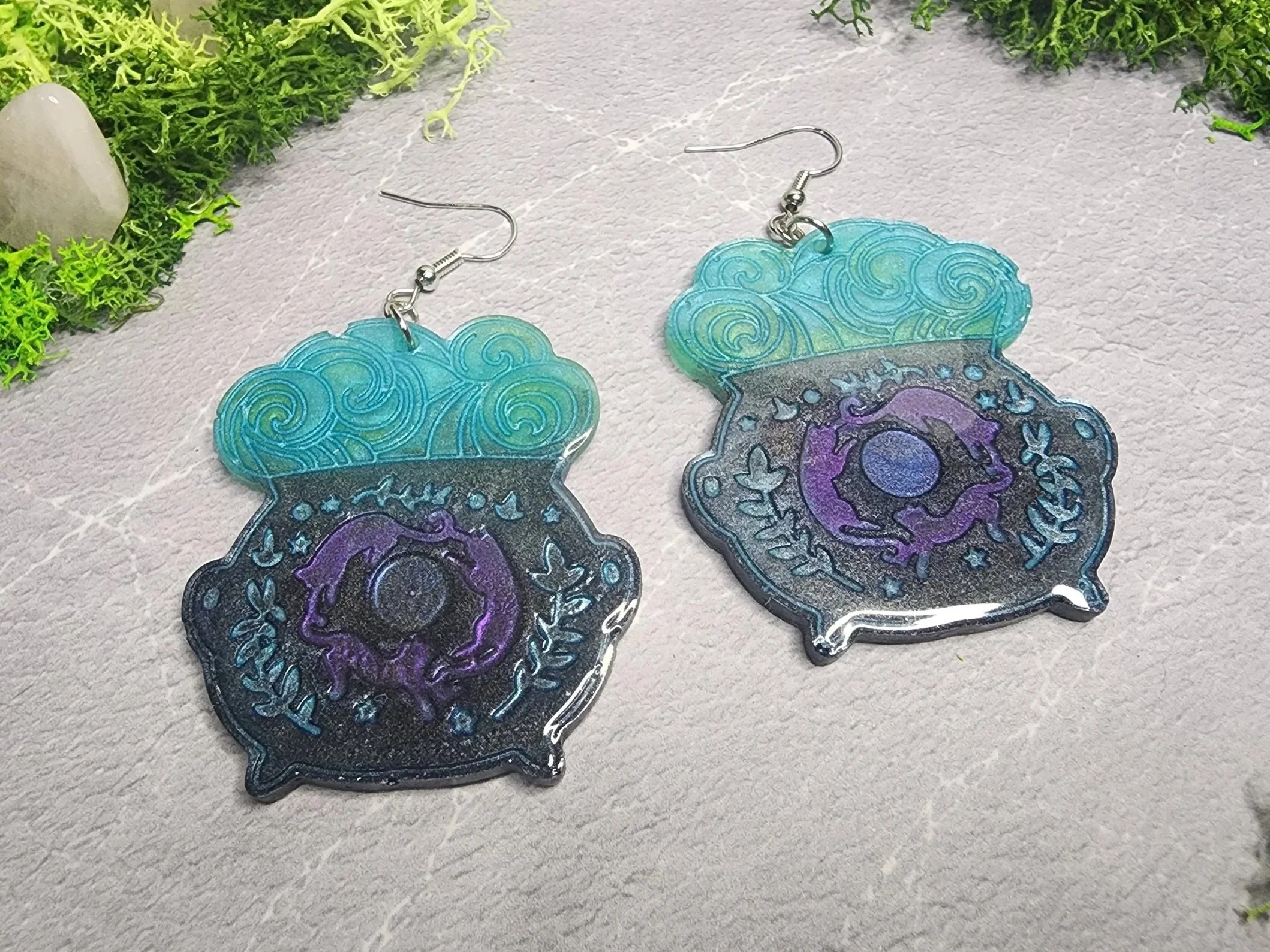 Close-up of purple and blue details on handmade UV resin cauldron earrings.