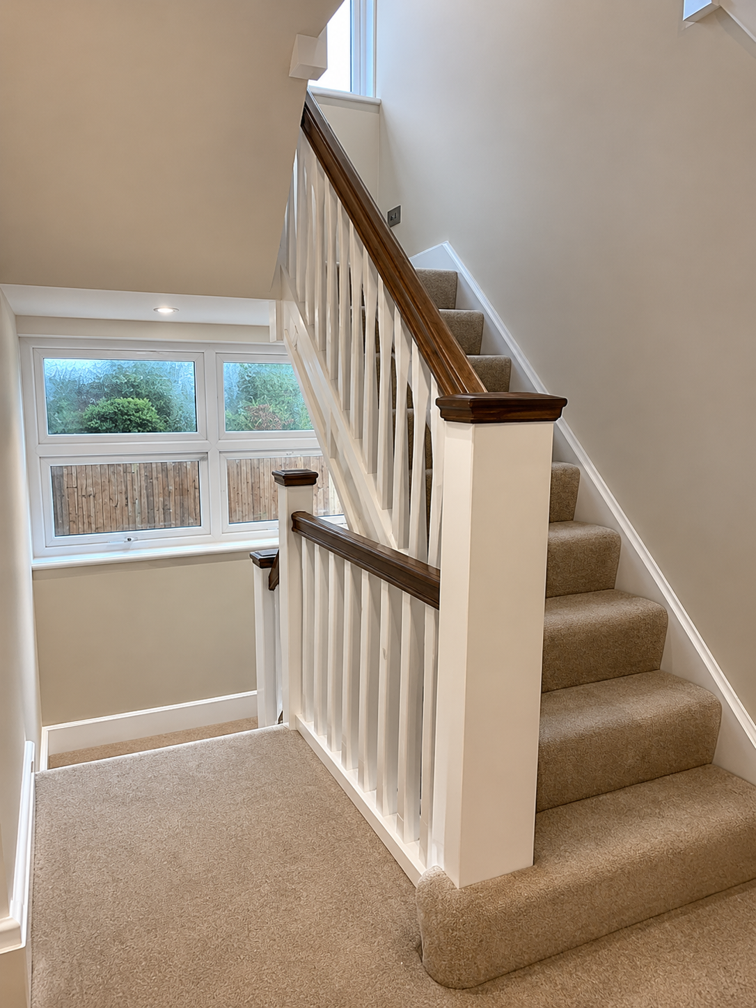 Carpeted staircase with white balustrade and dark wood handrail