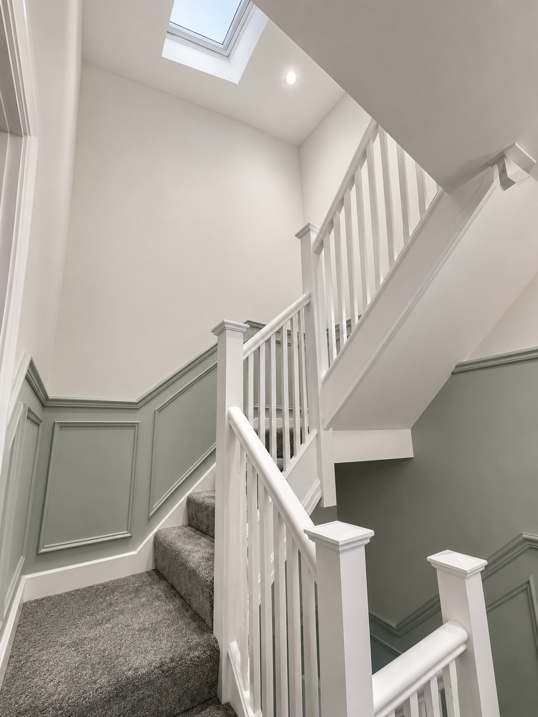 Painted staircase with wall panelling and traditional white balustrade