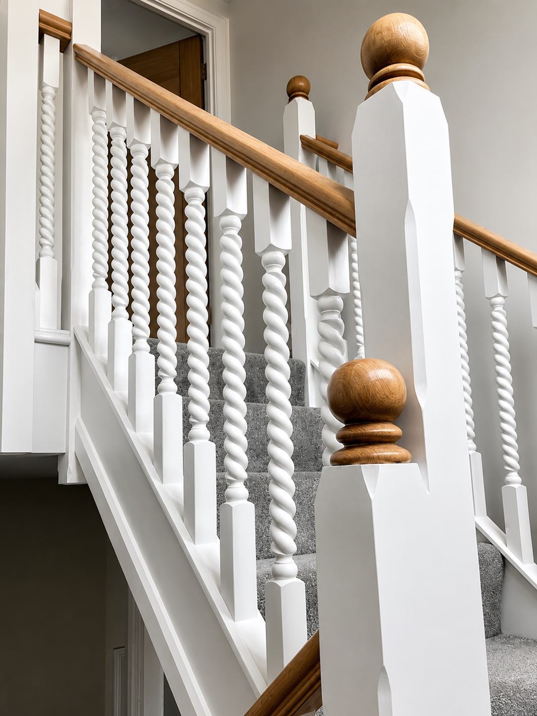 Traditional staircase with white twisted spindles and oak handrail