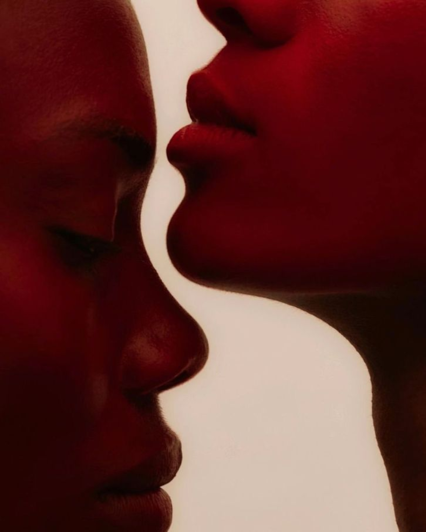 Close-up of two people's faces with their noses and lips close together, indicating an intimate moment.