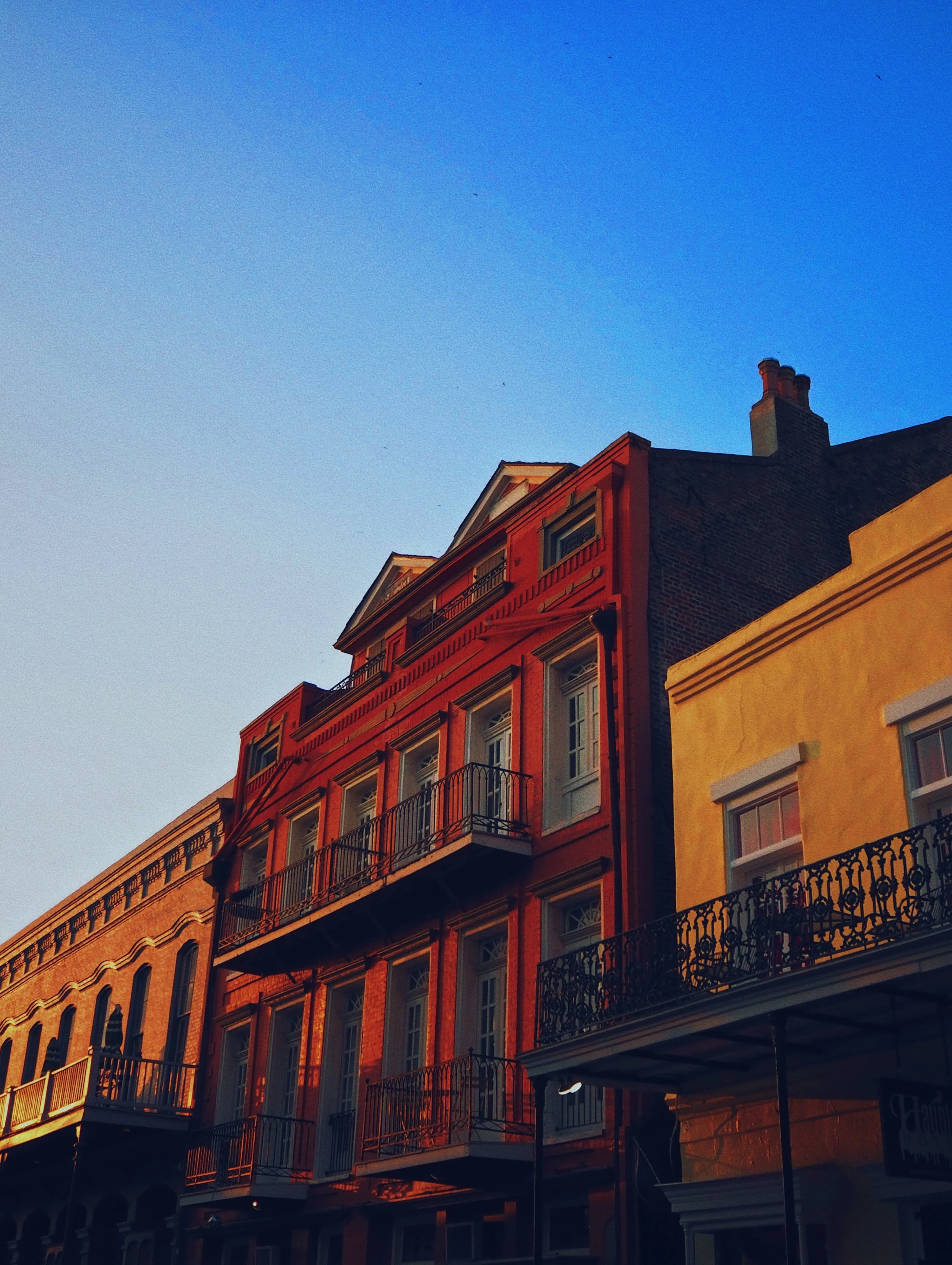 Multiple colorful buildings with balconies, under a blue sky during sunset.