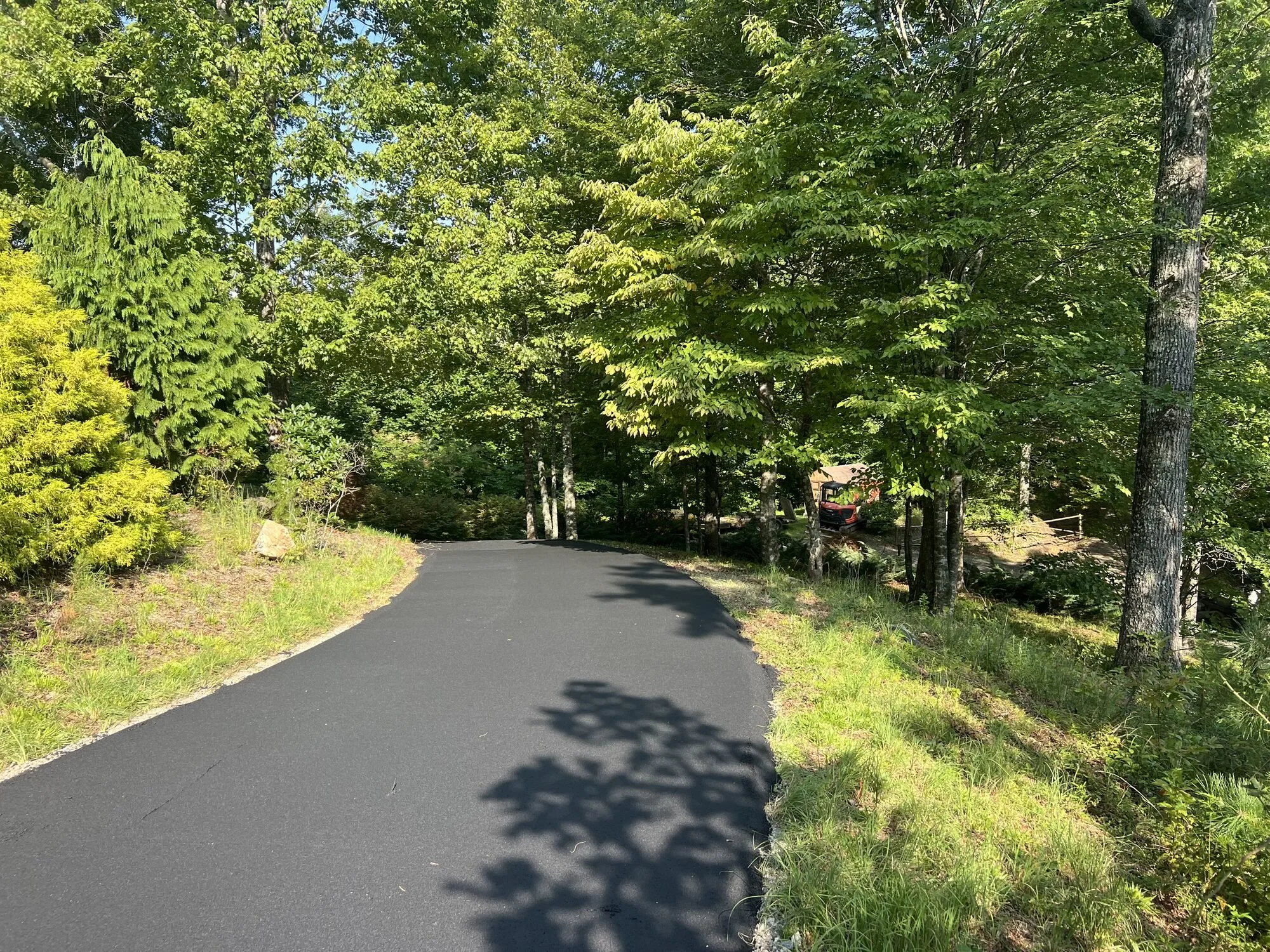 Freshly paved winding asphalt driveway through the woods in Bryson City, NC by Black Bear Paving