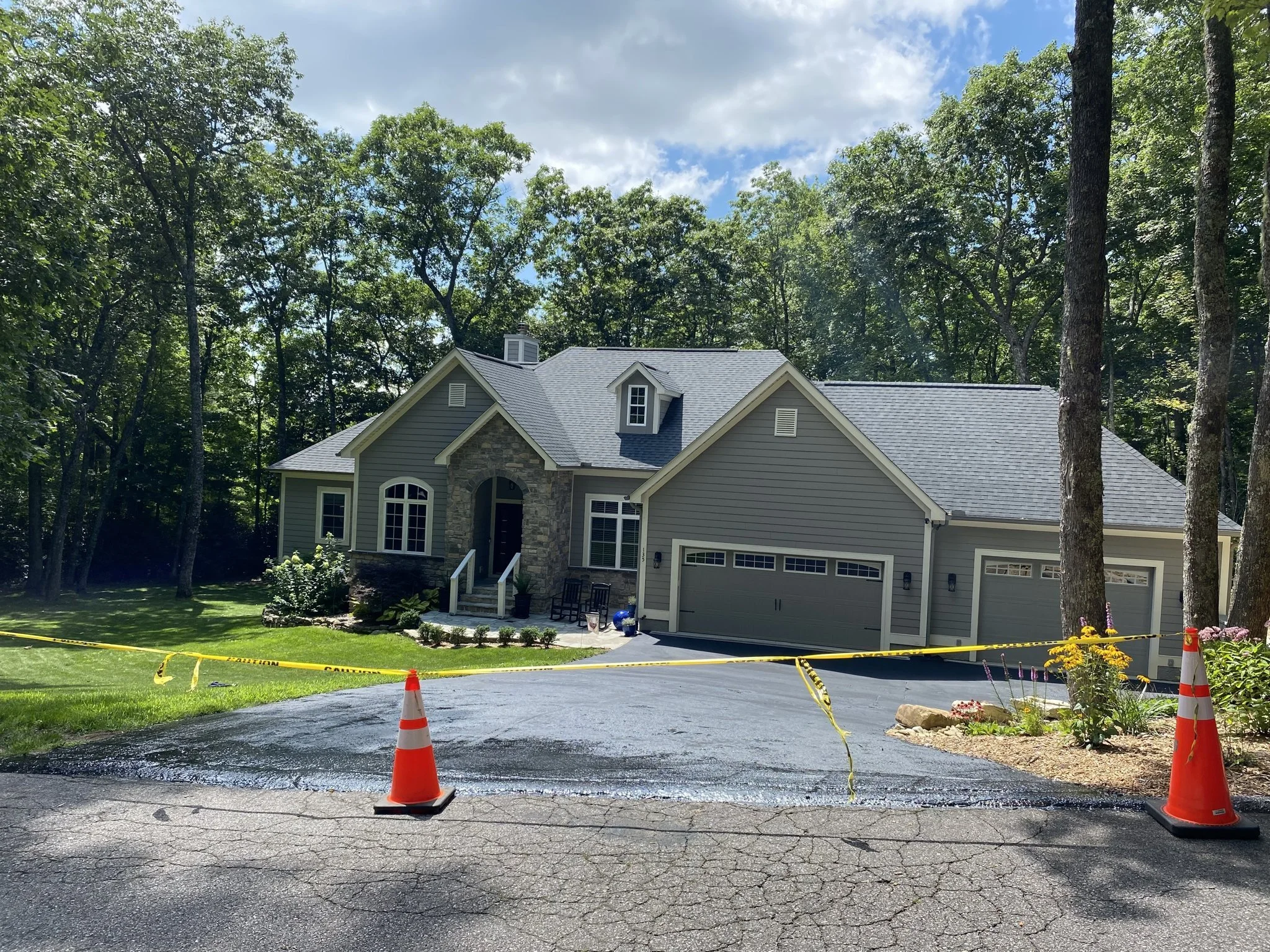 Wide view of a freshly sealcoated asphalt driveway at a Cashiers, NC home — sealcoating by Black Bear Paving