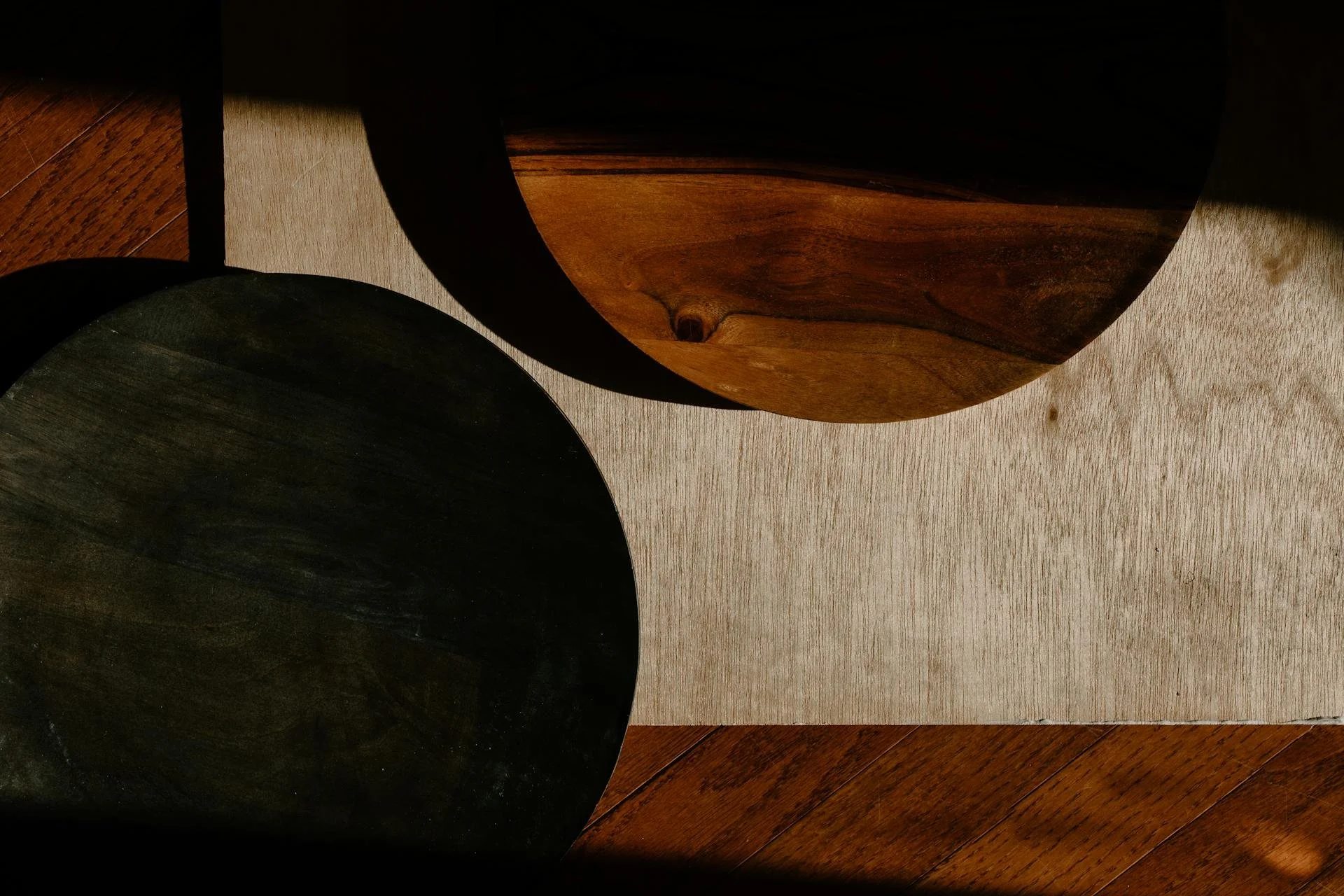 Wedding Website Design, Digital Wedding Stationery, Web Design and Branding for Wedding Professionals | Avelã White. Abstract composition of circular wooden objects with contrasting colors and textures, partially lit by sunlight, on a wood surface.