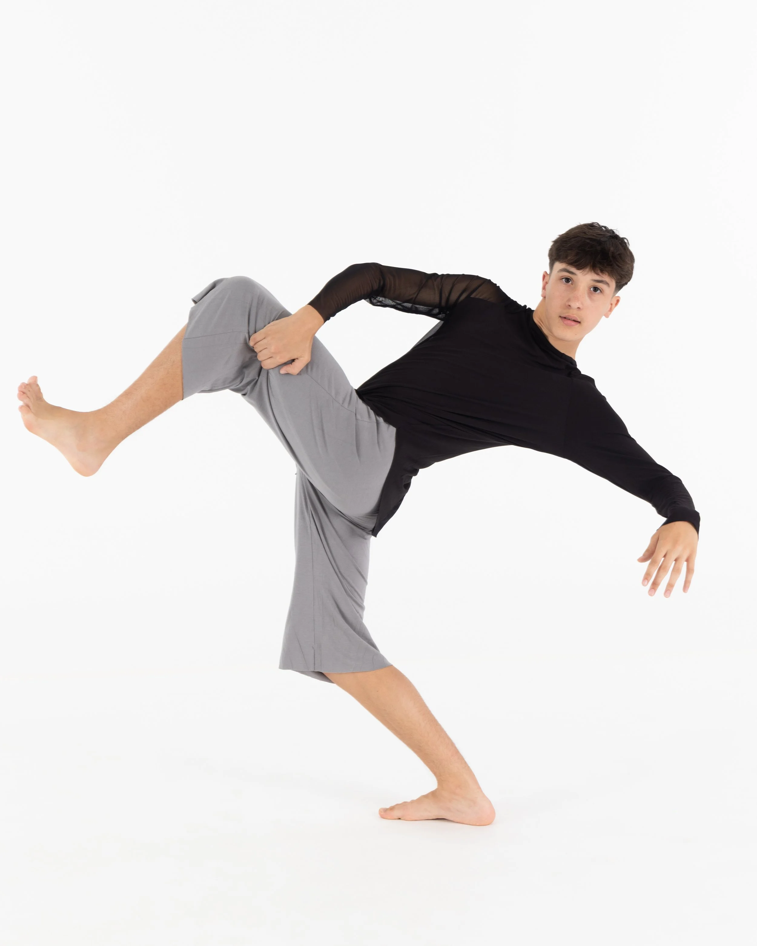 Young man performing a balancing yoga pose on a white background.