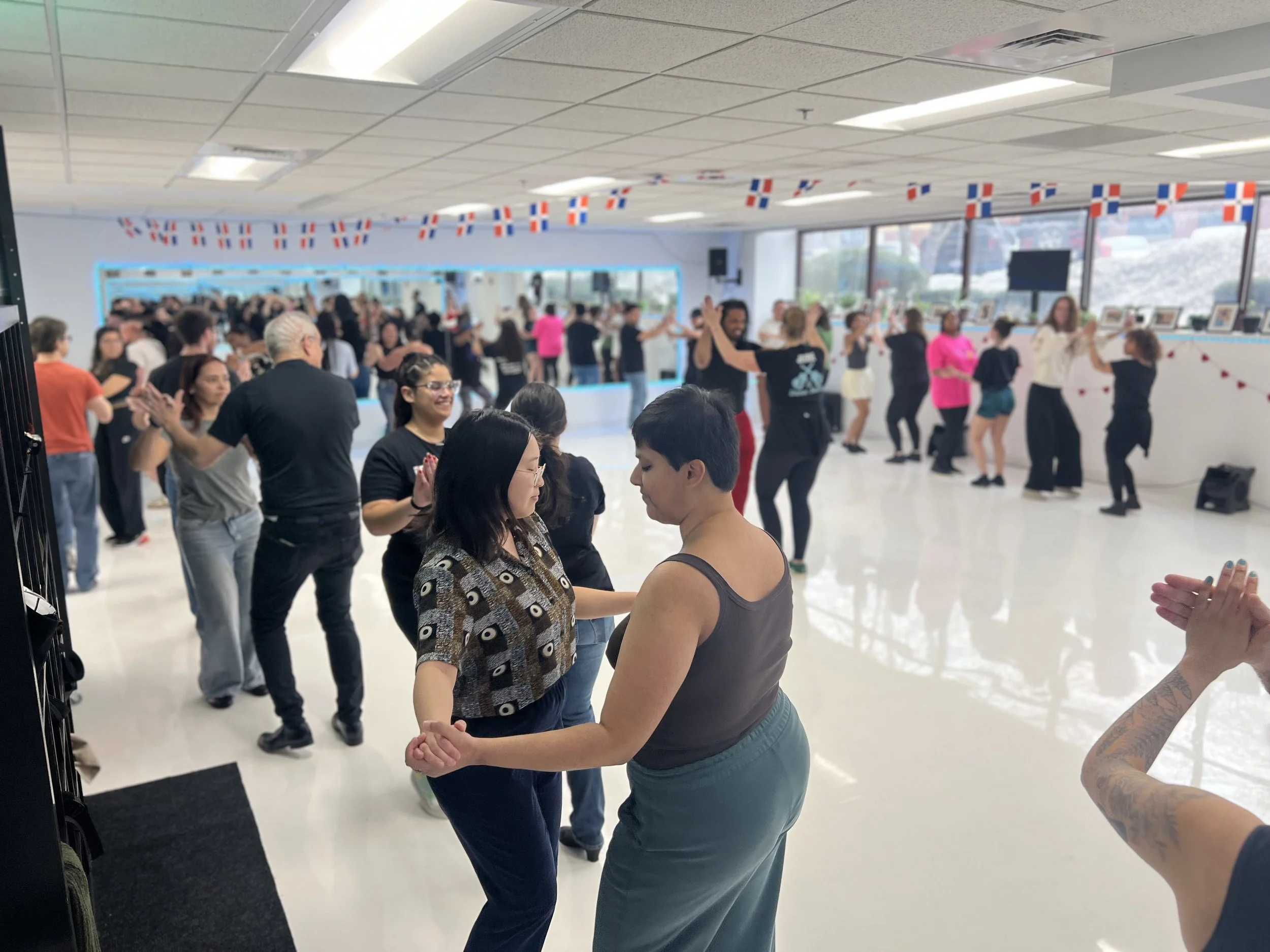 People dancing in a room decorated with small flags hanging from the ceiling.