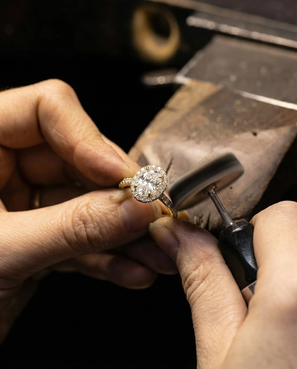 Jemand arbeitet an einem Ring mit einem Diamanten auf einer Schleifmaschine in einer Werkstatt.