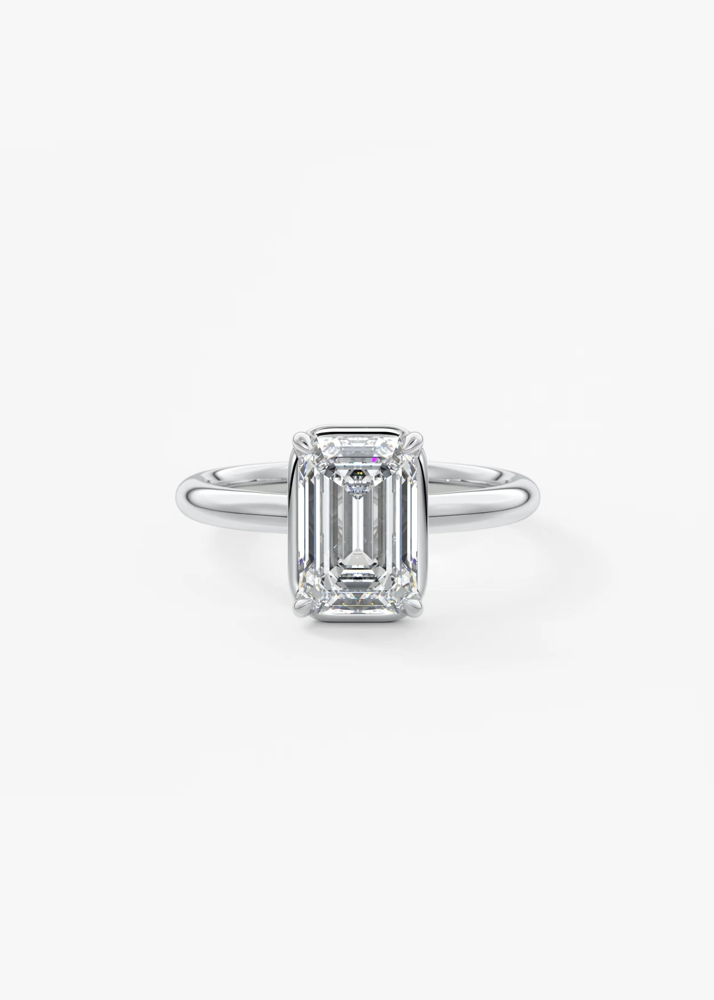 Ein eleganter Verlobungsring mit einem großen rechteckigen Diamanten in der Mitte, umgeben von kleineren Diamanten, auf einem weißen Hintergrund fotografiert.