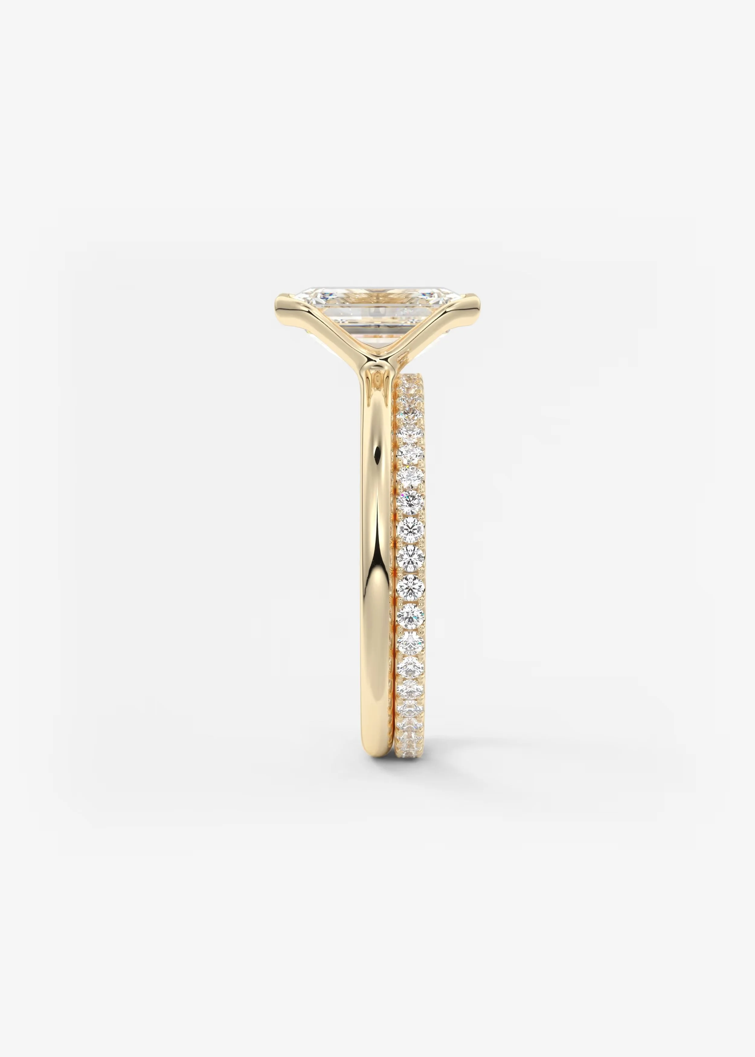 Zwei goldene Ringe, einer mit einem großen Princess-Cut Diamanten auf der Spitze, der andere mit mehreren kleinen Diamanten entlang des Rings, gegen einen weißen Hintergrund.