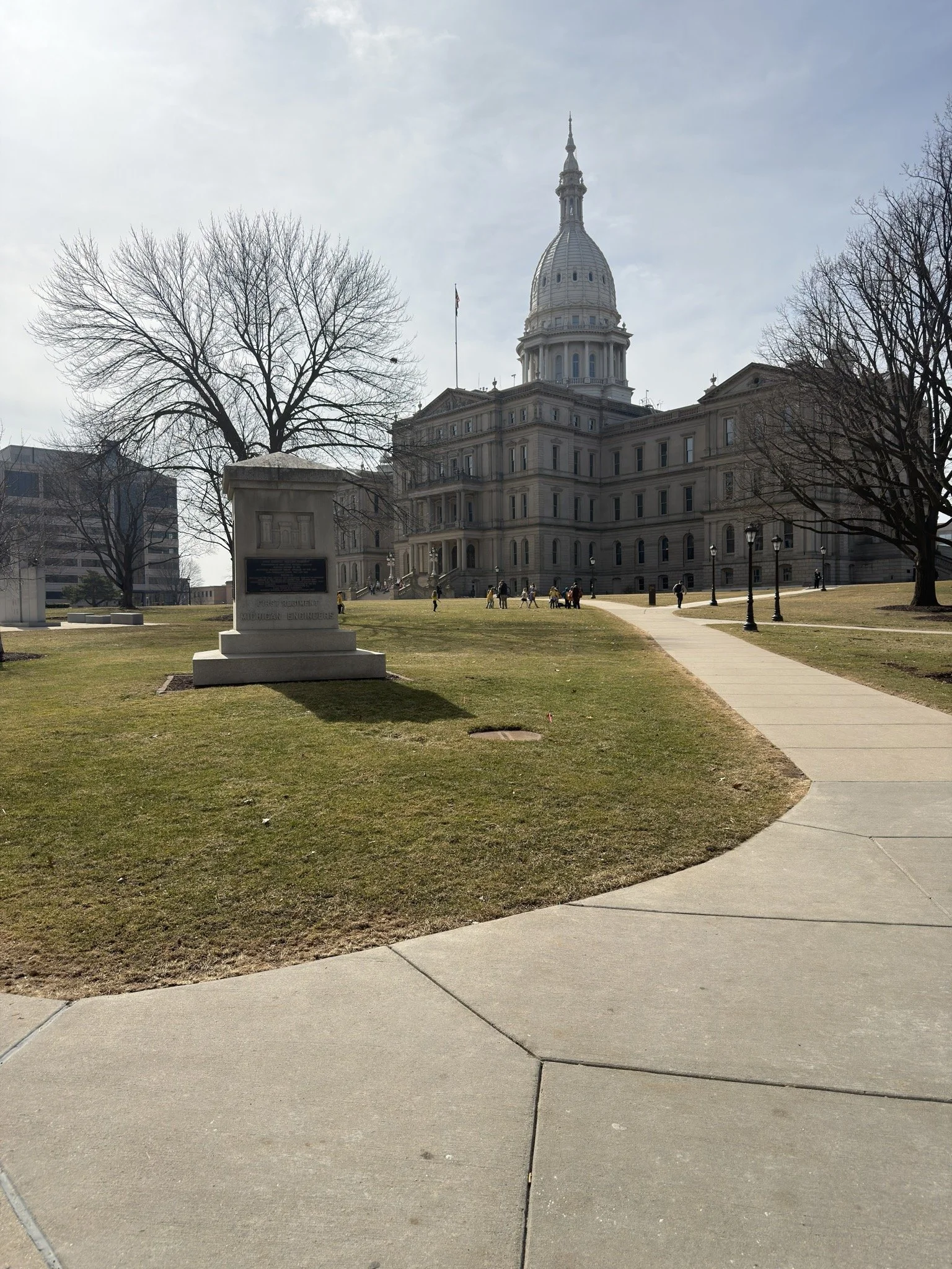 The Michigan State Capitol in Lansing with a walkway leading toward the building.