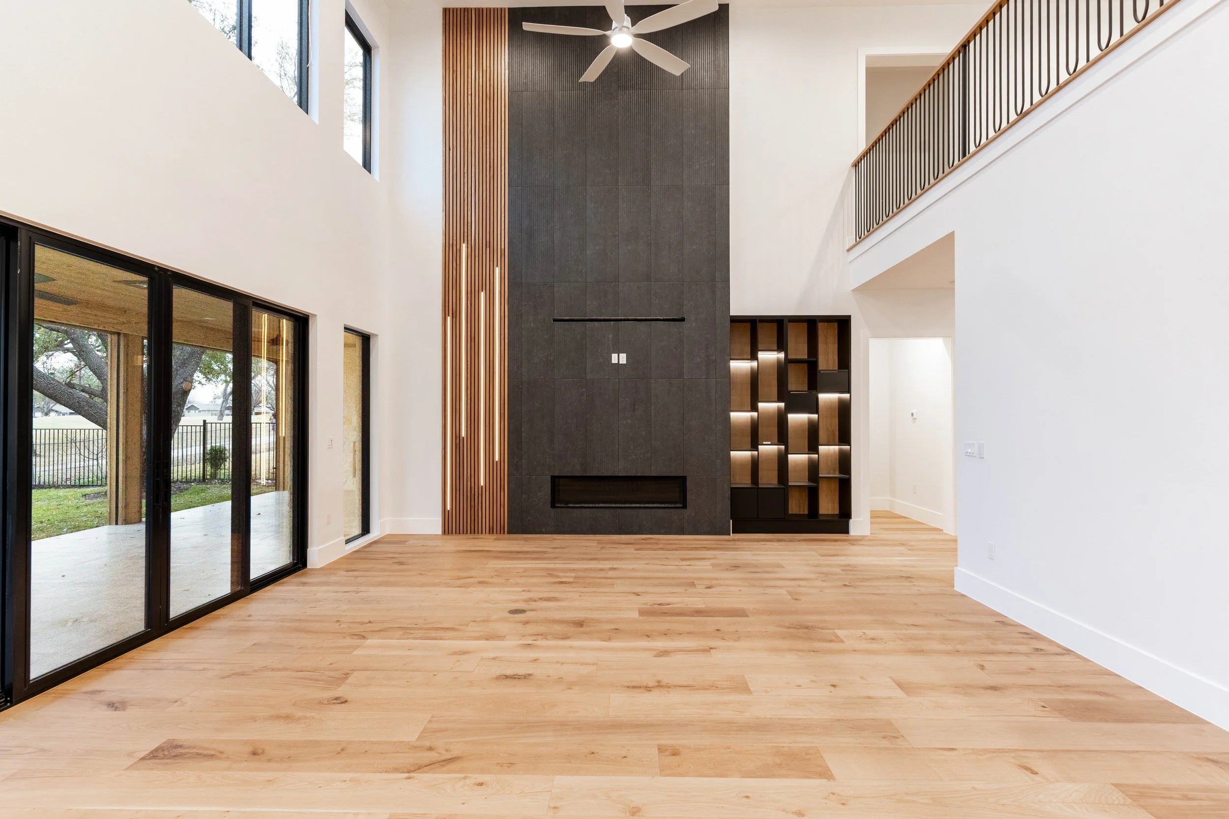 Custom-home interior with light wood flooring, dark-framed glass doors, and warm wood accents.