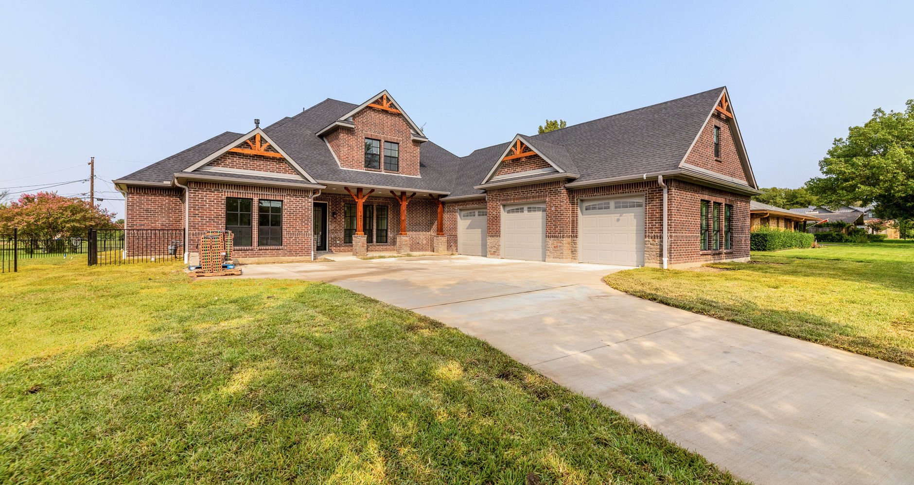 Brick-and-stone custom home with a covered entry, three garage bays, a concrete driveway and front lawn.