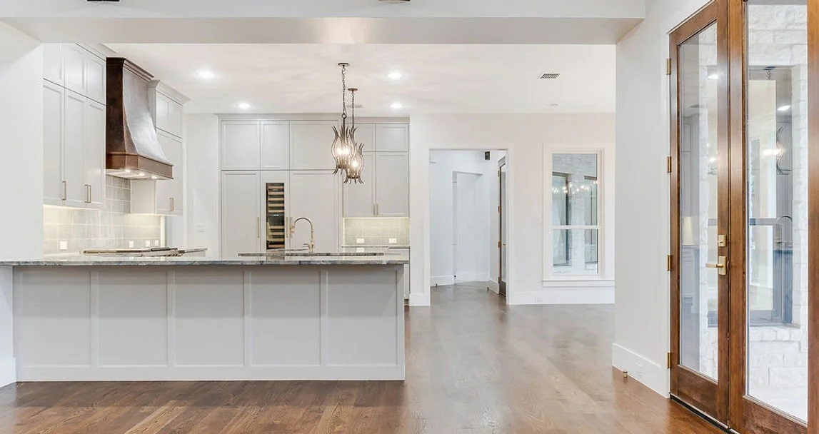 Bright white kitchen with large island and stainless range at 13628 Braemar Cir custom home in Farmers Branch, Texas