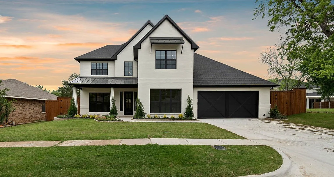 Two-story white custom home with dark rooflines, black-framed windows and a front lawn at 2525 Danny Lane.