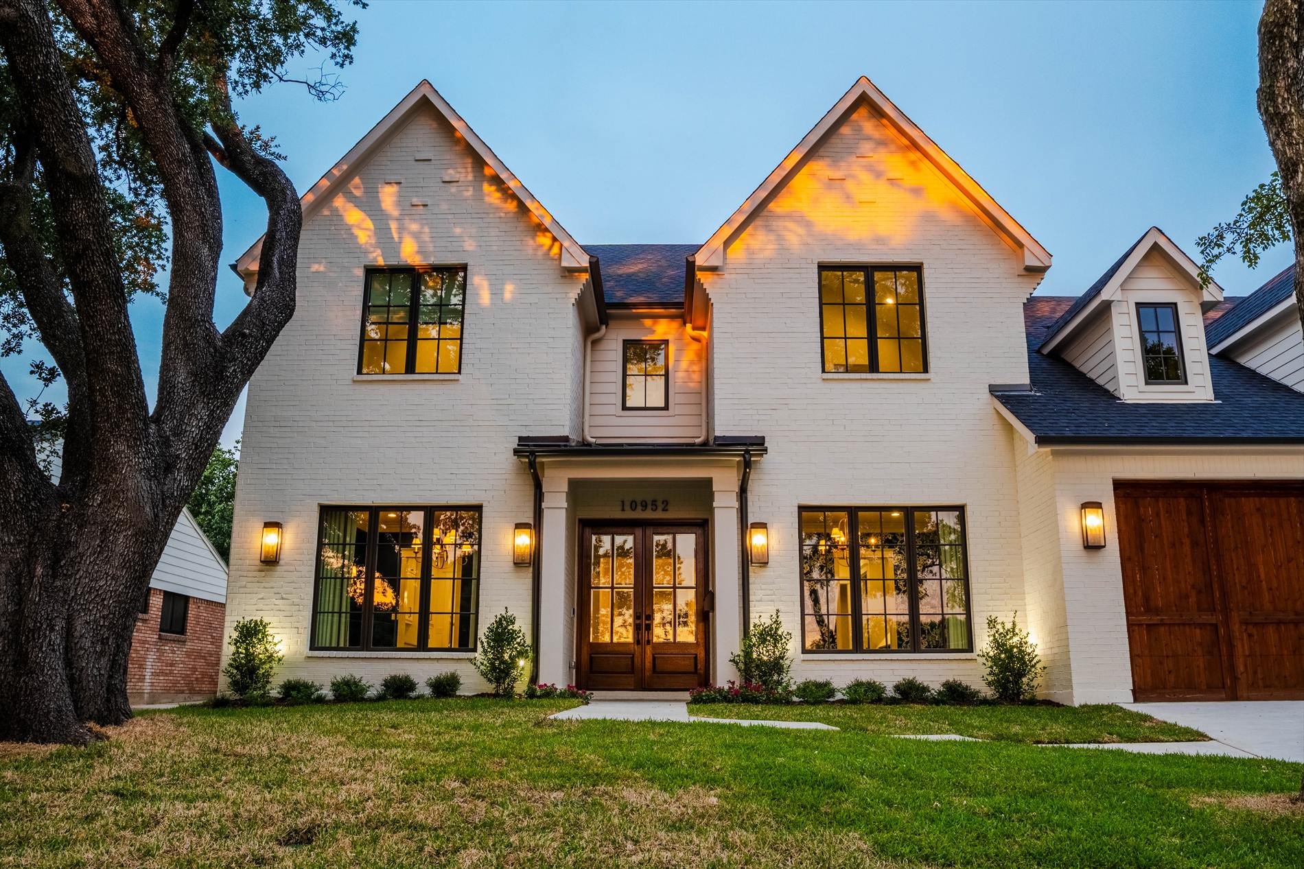 Two-story white custom home exterior at dusk with a landscaped front lawn at 1095 Lathrop Dr.