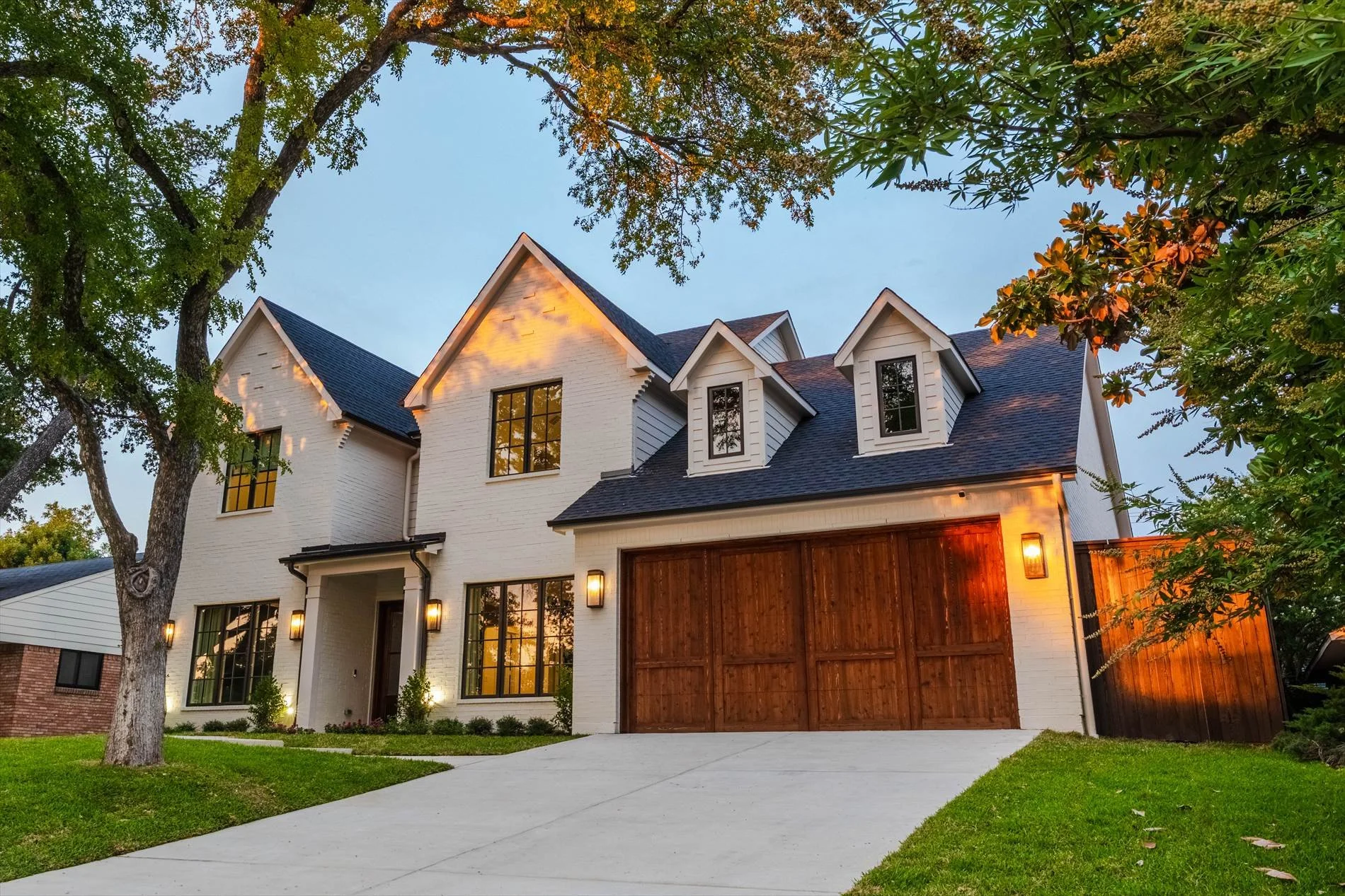 Front exterior and driveway with wood garage doors and mature trees at 1095 Lathrop Dr.