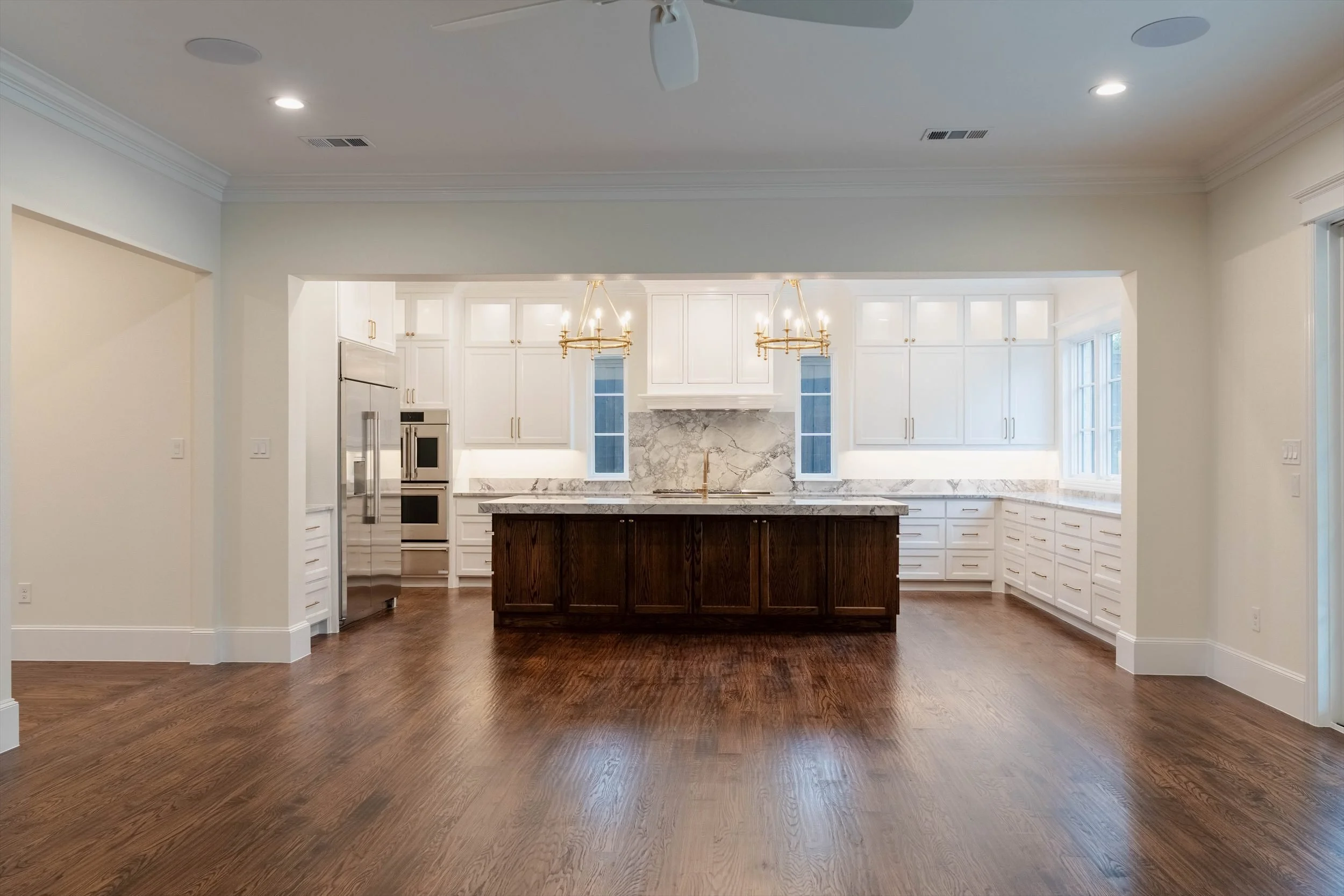 Open kitchen with a dark island, white cabinetry and wood flooring at 1095 Lathrop Dr.
