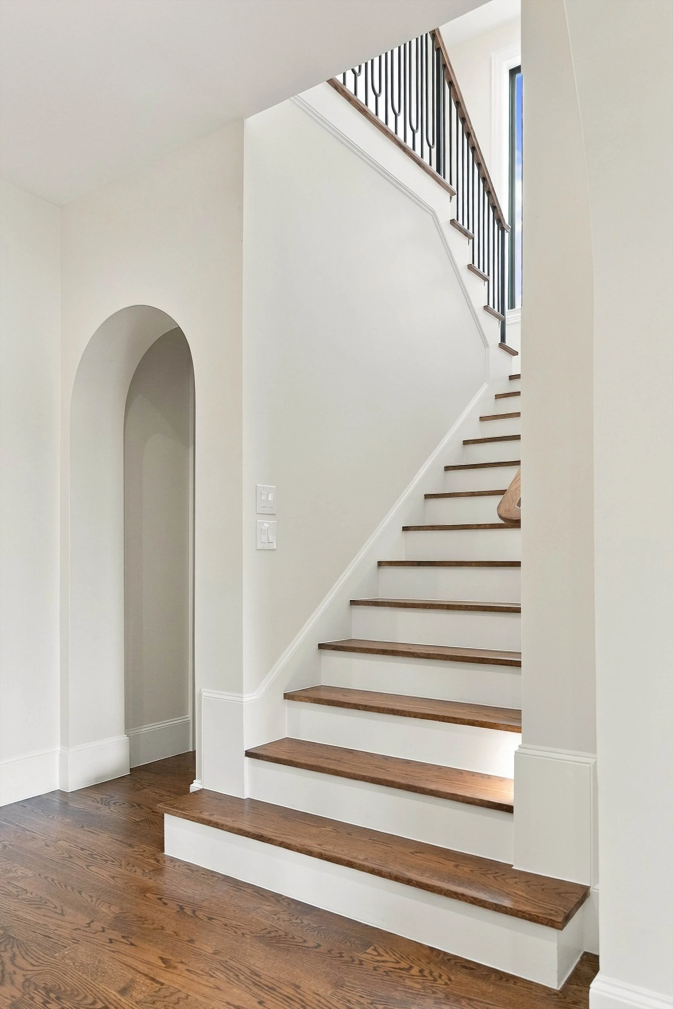 Staircase with wood treads and arched wall detail at 3368 Dorado Beach Dr in Dallas, Texas.