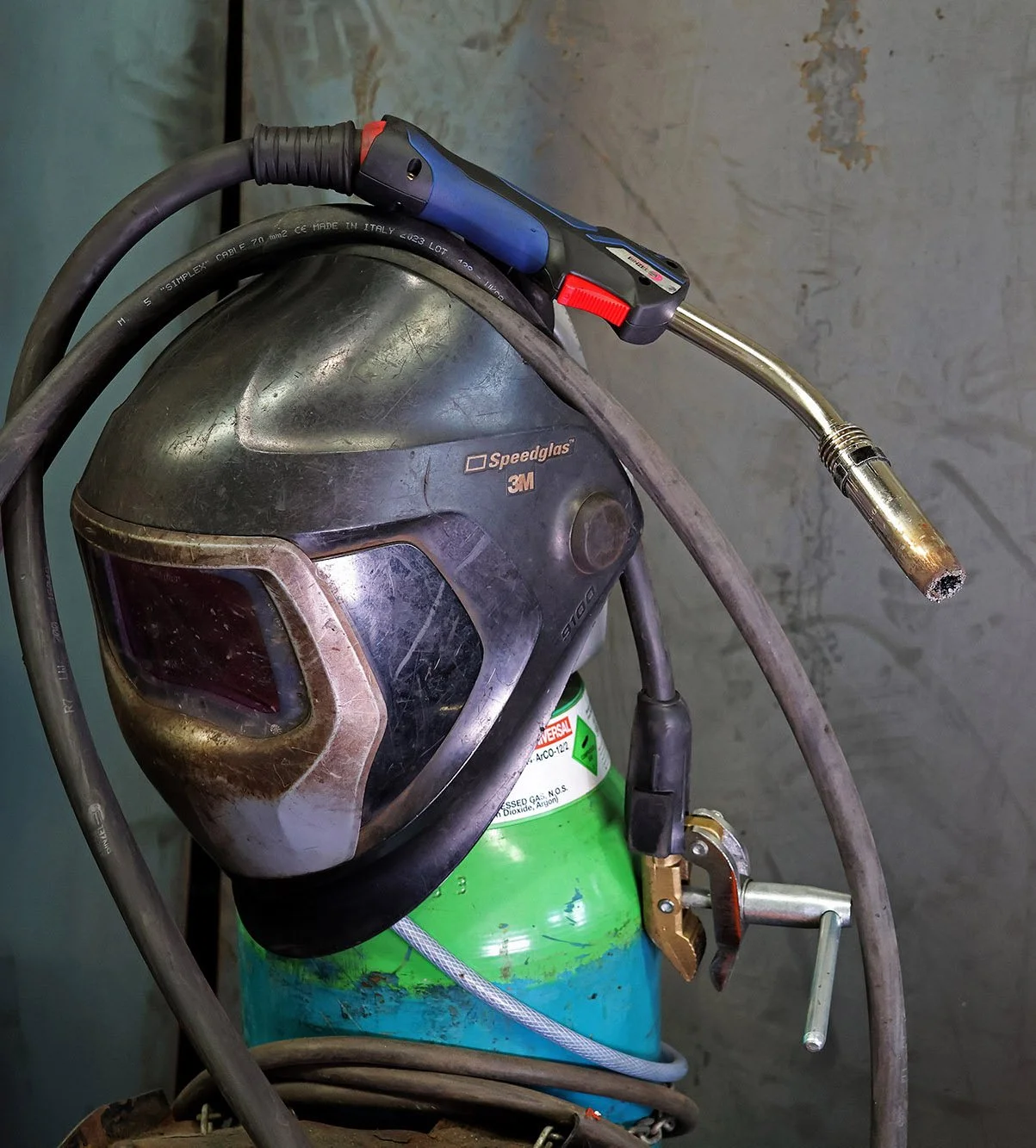 Professional welding helmet and MIG welding torch ready for metal fabrication and engineering work.