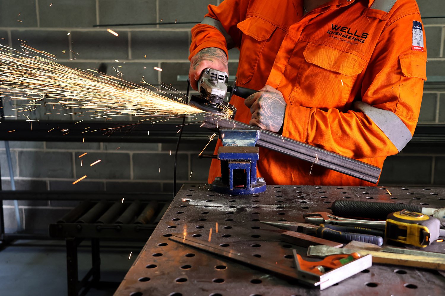 Grinding structural steel during professional metal fabrication using an angle grinder.