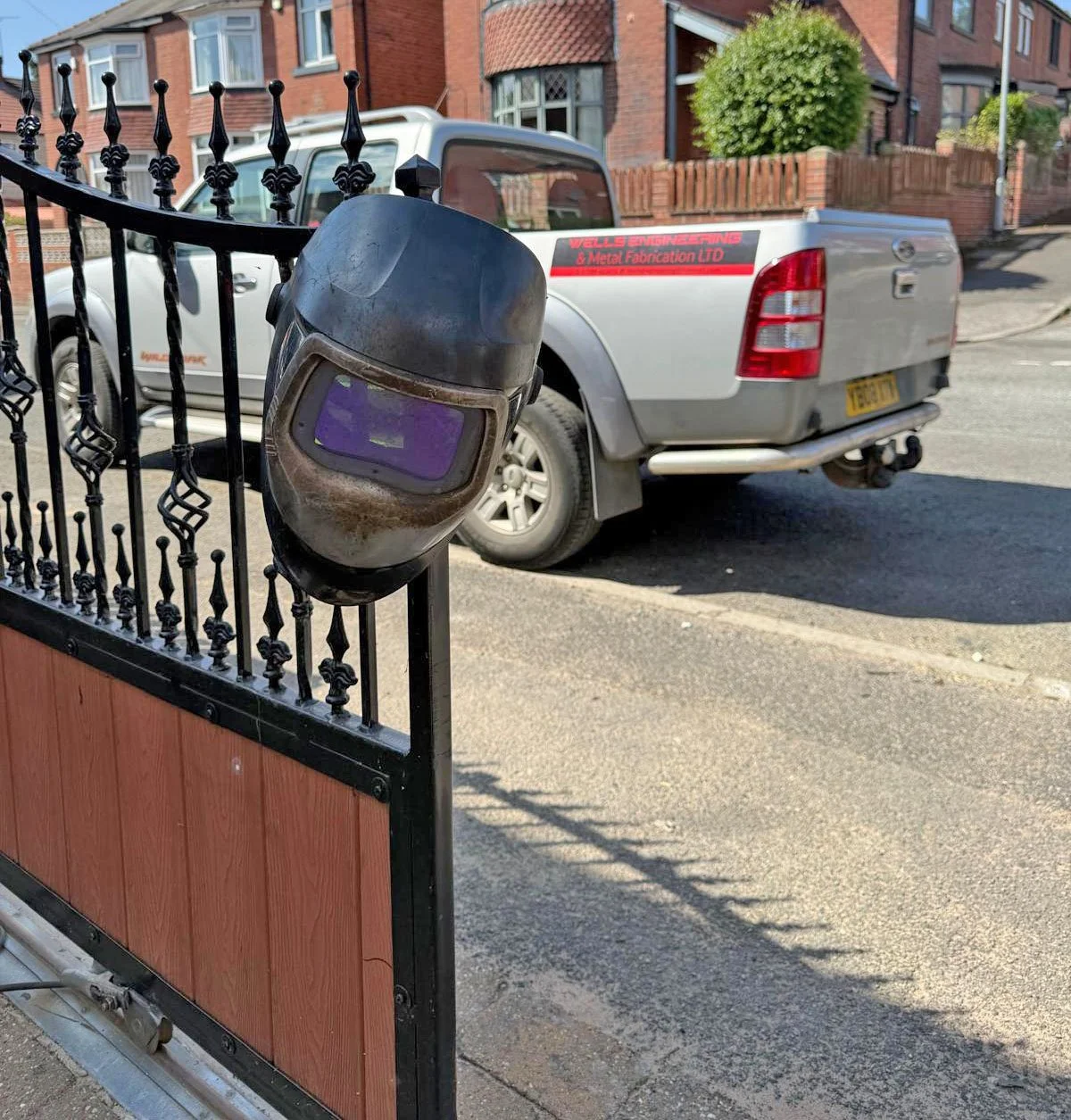 Professional welding helmet hanging on a gate, in readiness for use in mobile welding on-site repair and modification