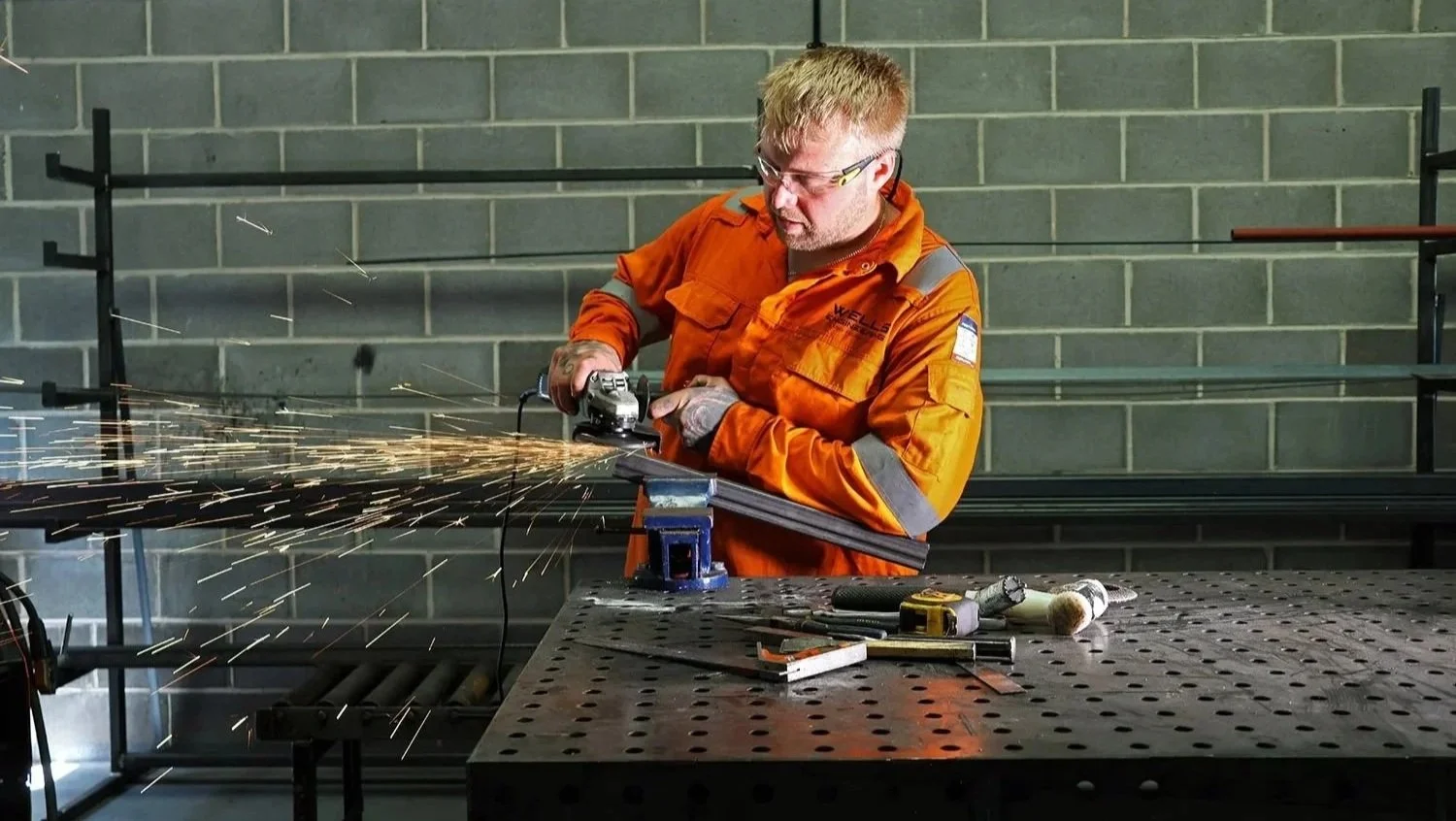 Grinding structural steel during professional metal fabrication using an angle grinder.