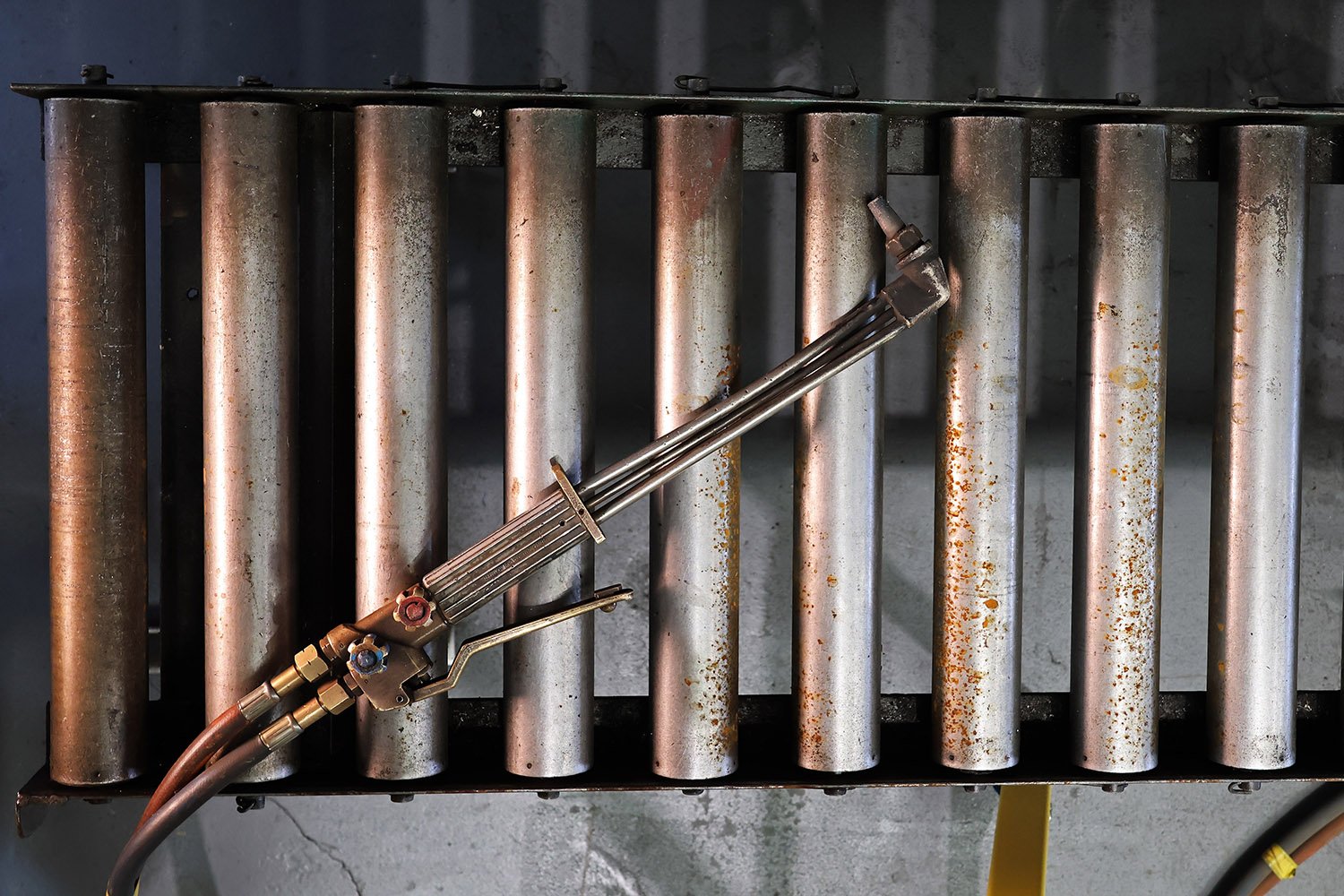 Oxy-fuel cutting torch and steel fabrication equipment in a professional engineering workshop.