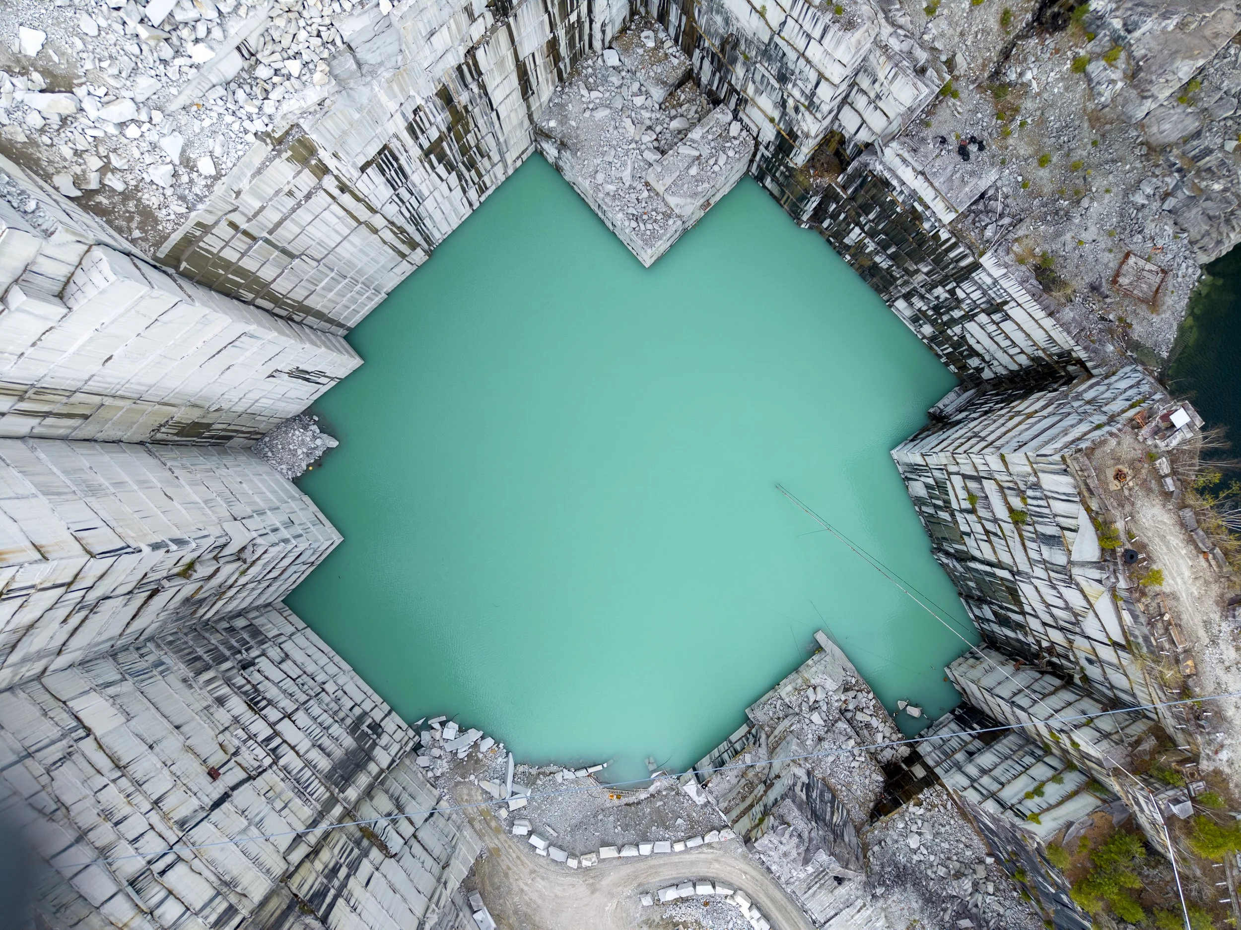 Aerial drone photography of a quarry with a turquoise water reservoir.