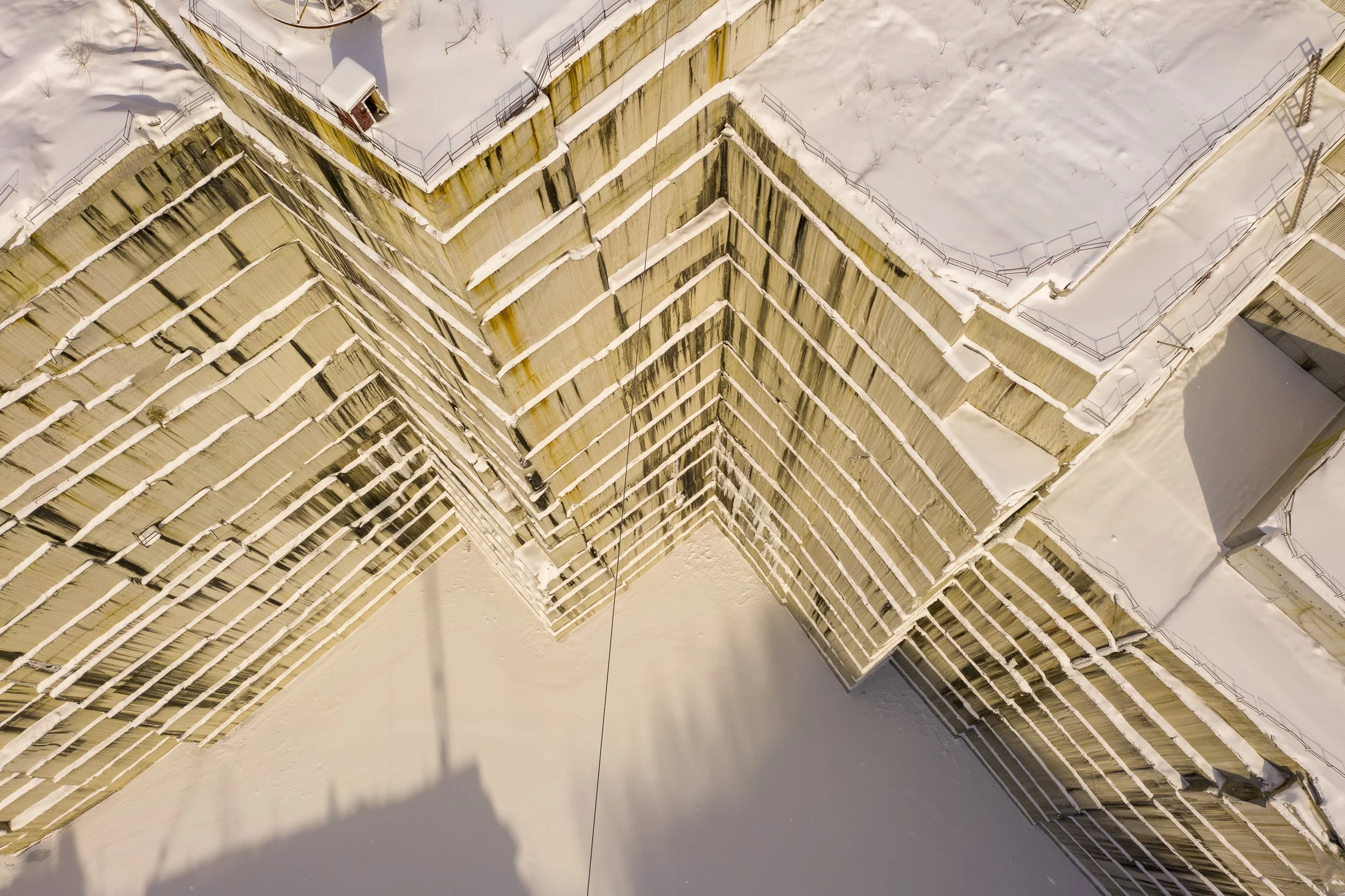 An aerial drone photo of a snow-covered quarry, metal railings along the edges, and some snow buildup on the structure.