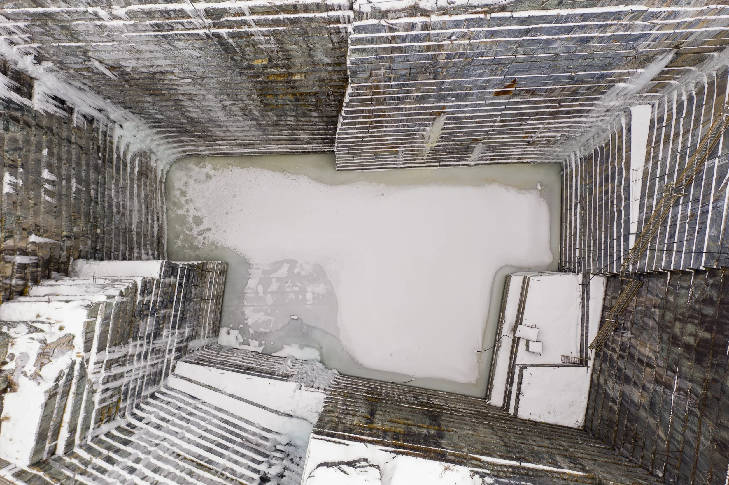 Aerial drone photography of a quarry in winter with snow-covered surroundings.