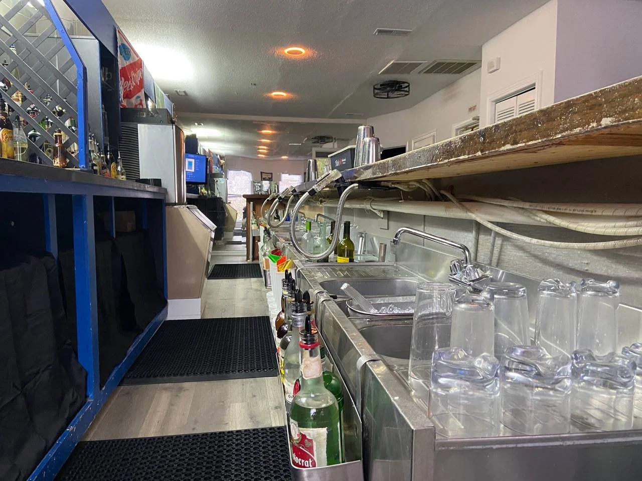 Close view of a service well with stainless sinks, ice bin and stacked glassware.