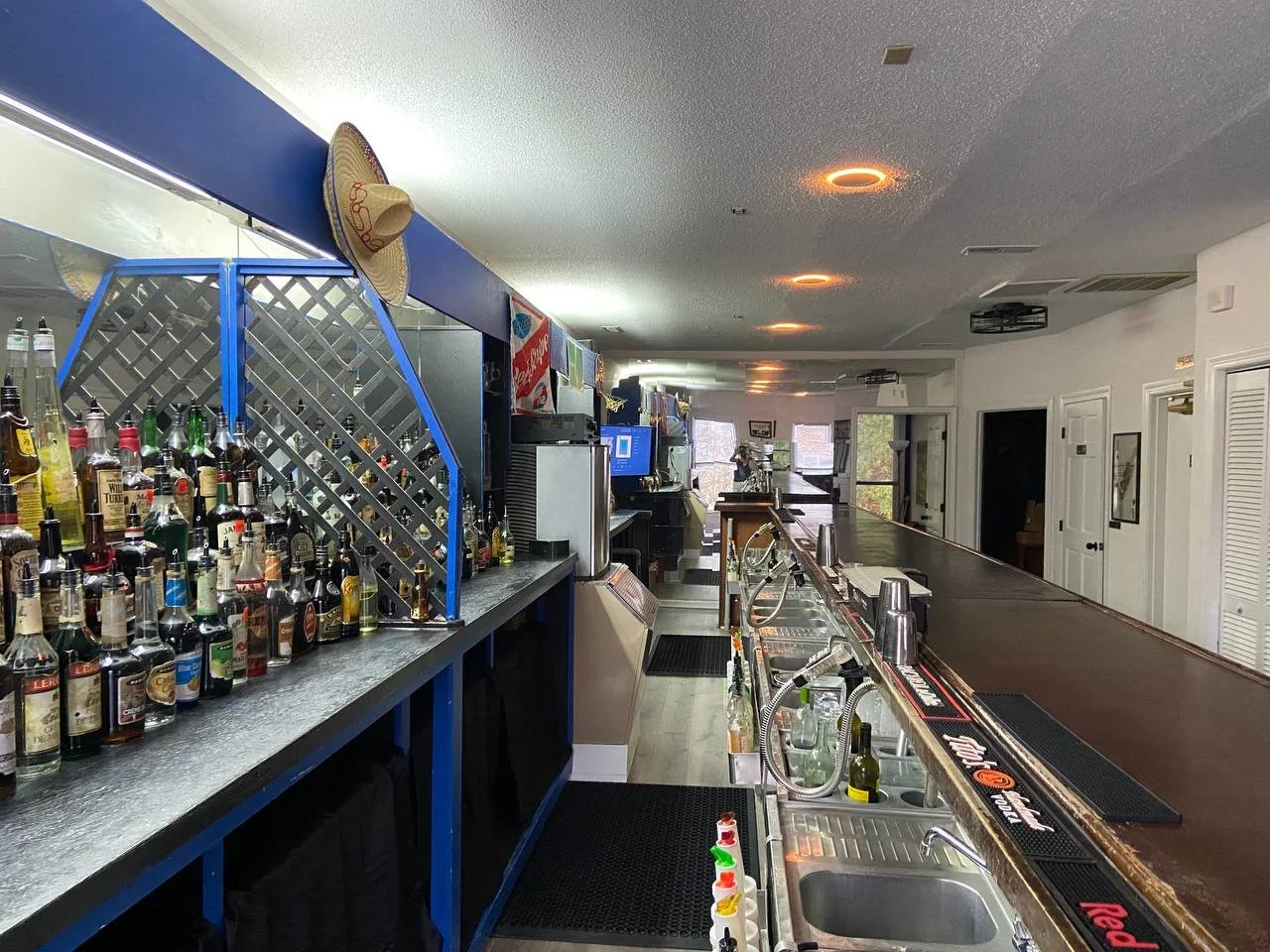 View down the back of the bar showing the speed rail, soda gun and back bar shelving.
