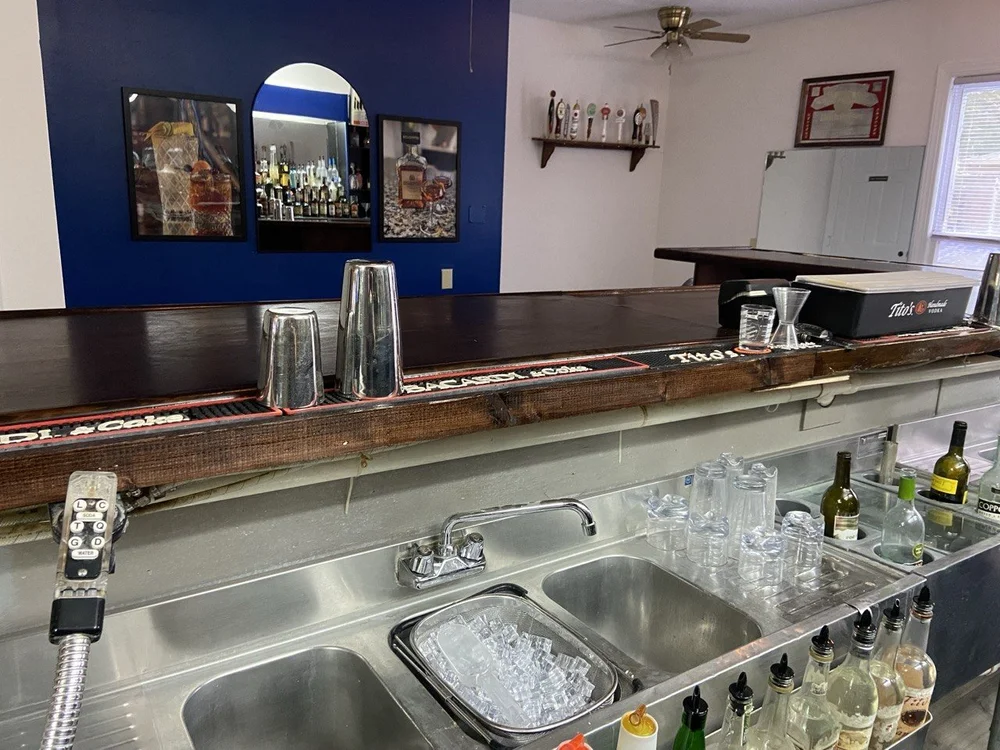 Shaker tins, a jigger and bar mats arranged on the finished bar top.
