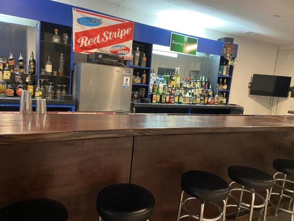 The bar top and back bar with the room's screens and signage behind.