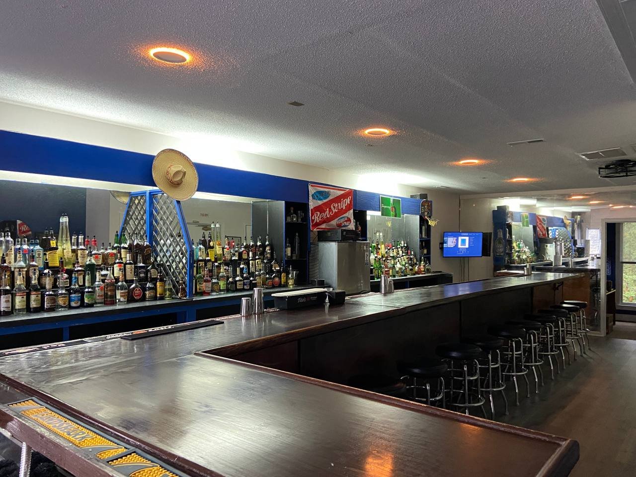 The renovated training bar at Bartending Master Class, seen down its full length with stools along the rail.