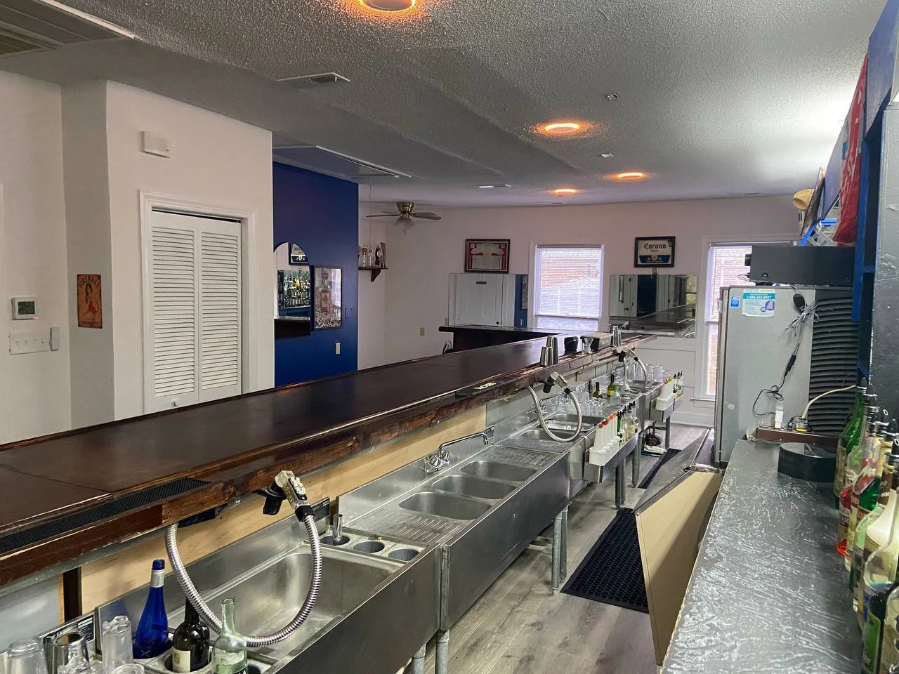 Multiple stainless sink stations along the length of the bar with windows beyond.