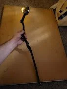 Person holding a black stick with a small round object at the top