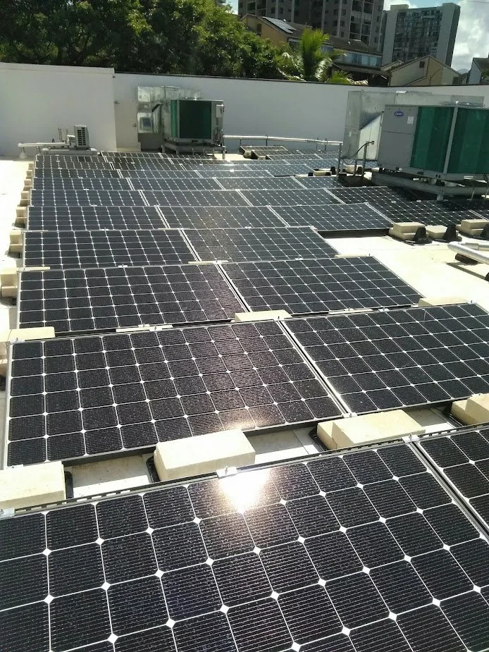 Solar panels installed on a rooftop with city buildings and trees in the background.