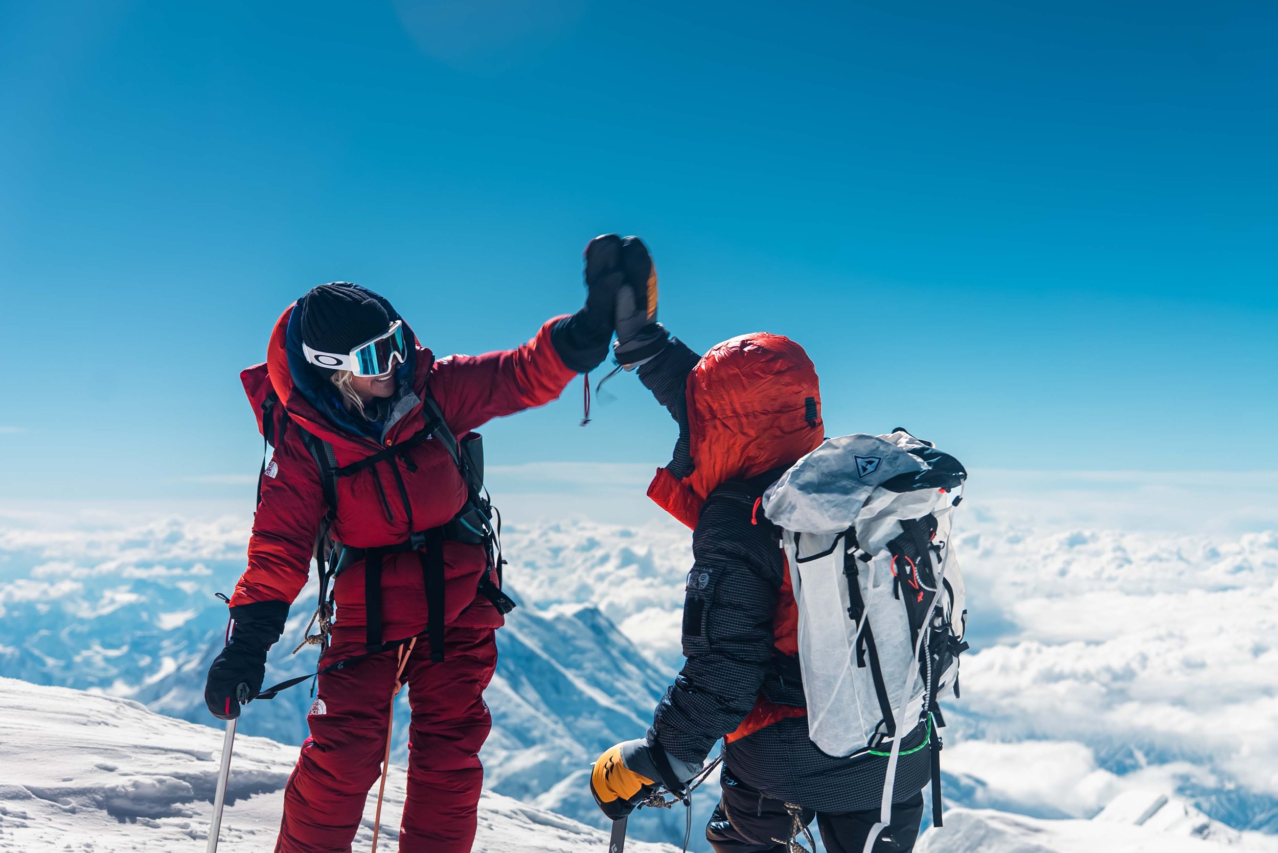 Two people high fiving each other on top of a mountain