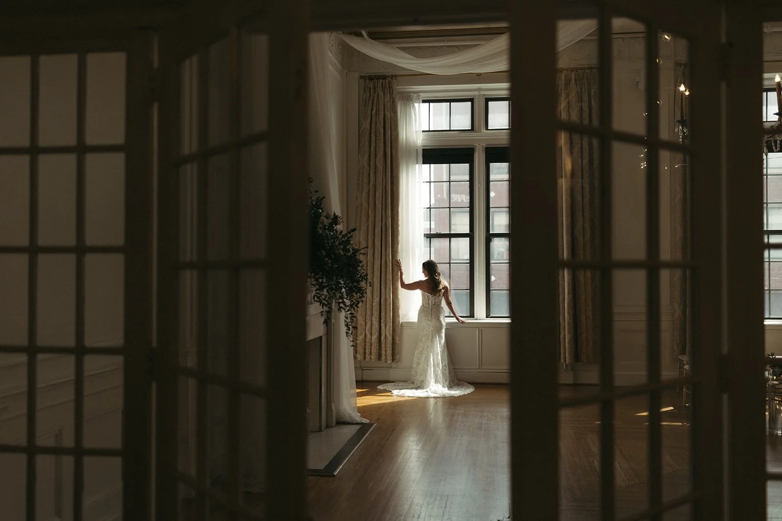 Bride poses in a window in historic ballroom
