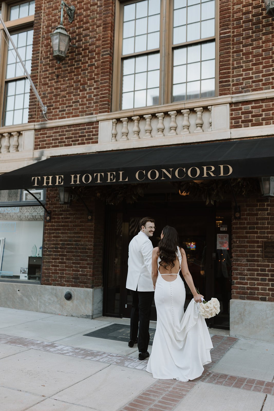 A couple stands outside wedding venue in downtown concord north carolina