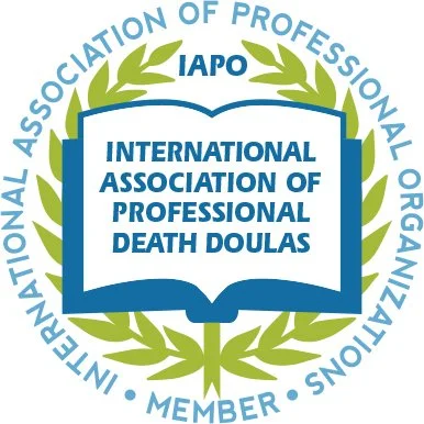Logo of the International Association of Professional Death Doula, with a blue open book at the center, surrounded by a green laurel wreath, and the organization's name and membership status written around it.