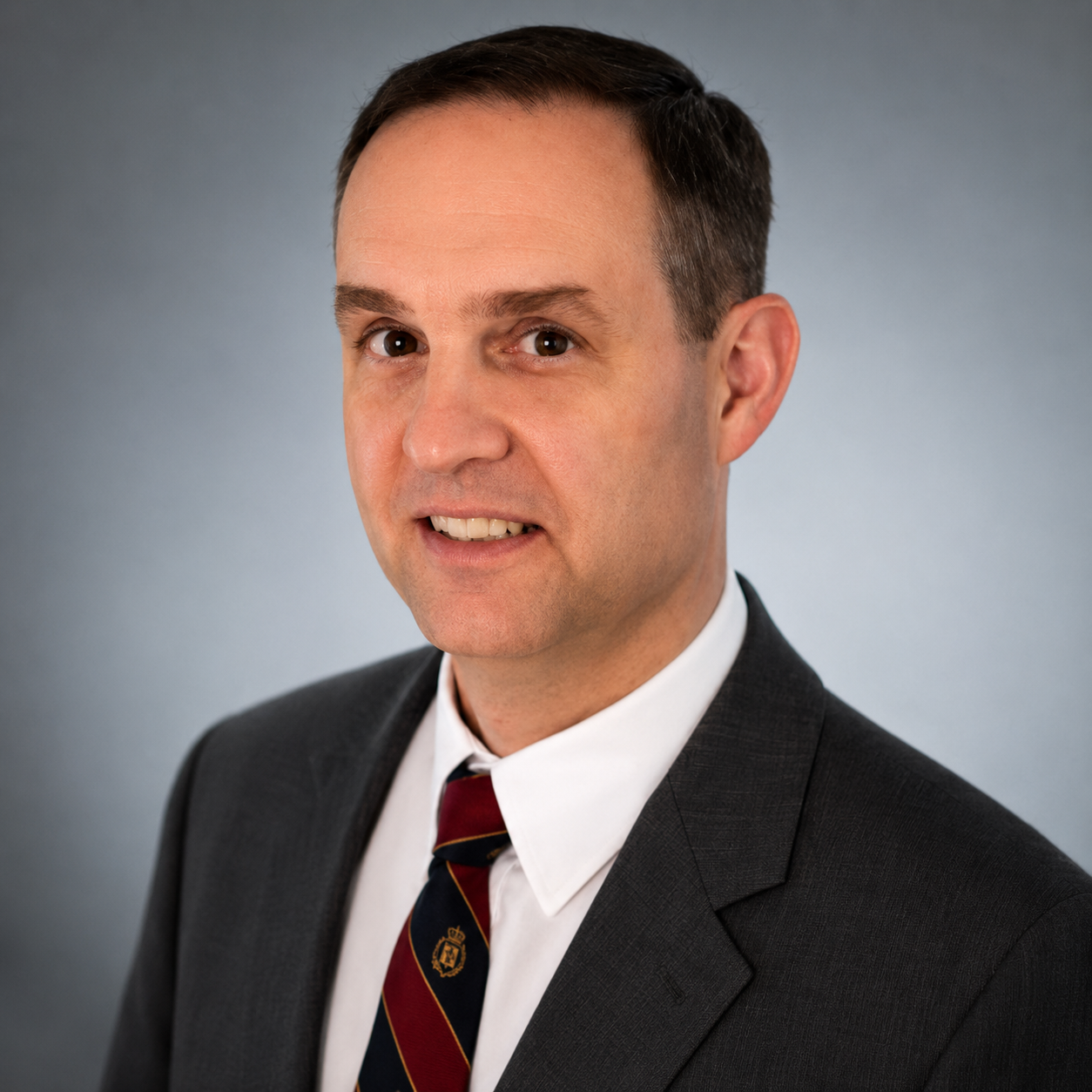 A professional man in a suit and tie posing against a plain background.