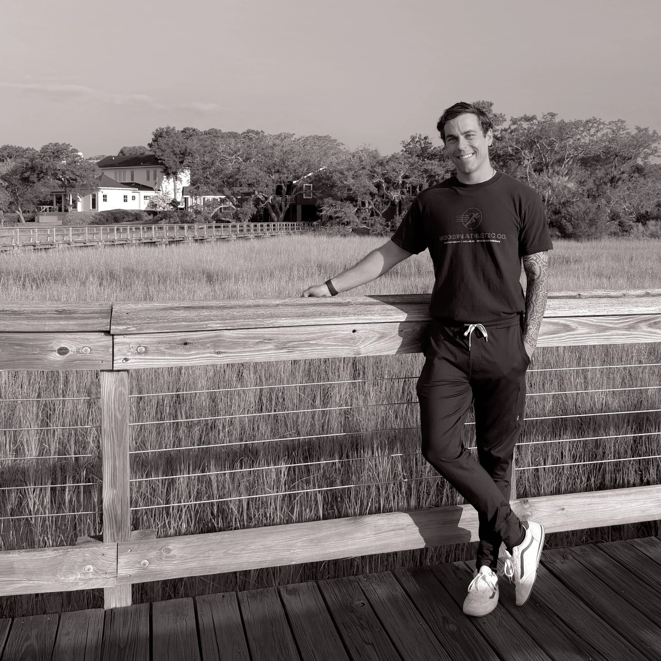 Forrest Campbell, PT, DPT, founder of Modern Athletic Co., standing by a waterfront railing in Shem Creek, Mount Pleasant.