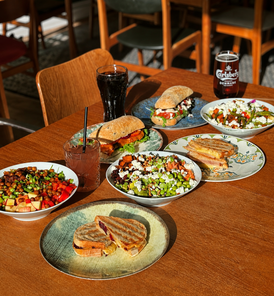 Bord med salater, sandwiches, snacks og sodavand på café Lucerna.