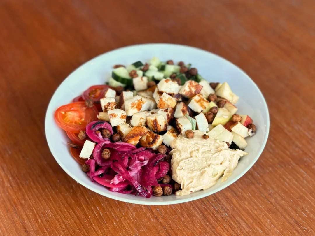 Halloumisalat med tomat, agurk, syltede rødløg, æble, halloumi og hummus.
